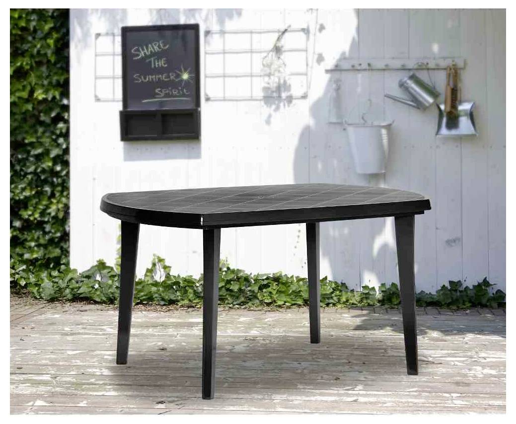 Sort udendørs terrassebord med fire ben på et træbræt ved siden af en hvid væg og haveværktøj.