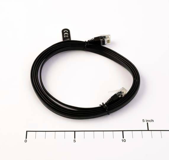 Oprullet sort Ethernet-kabel med RJ45-stik, vist på hvid baggrund med en 5-inch skala til størrelsereferencer.