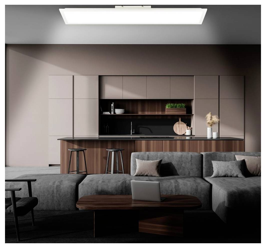 Moderne stue i åben planløsning med grå modulsofa, bærbar computer på sofabord og elegant køkken med ø og barstole i baggrunden.