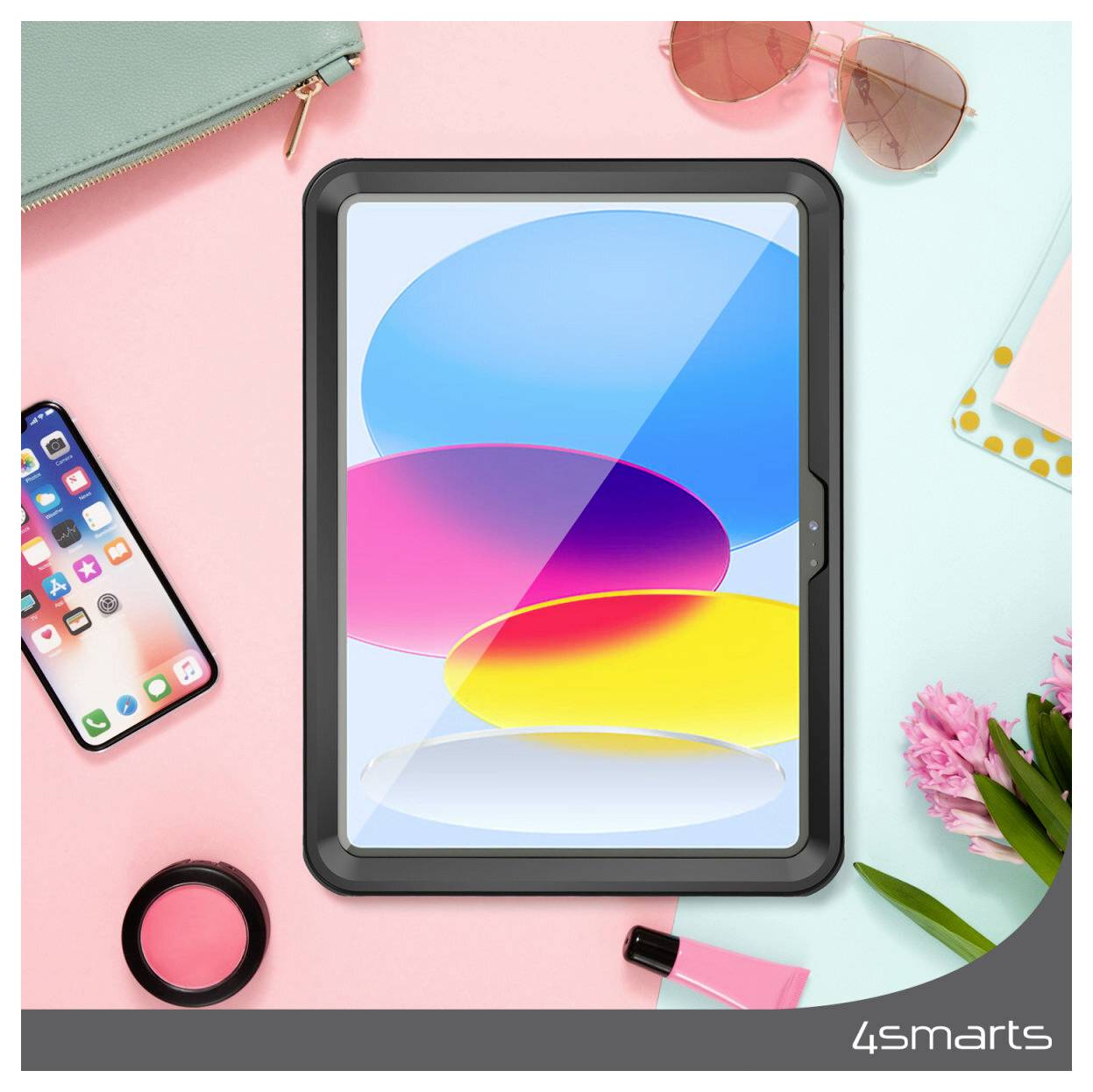 Skrivebordsbillede set oppefra med en tablet, der viser farverige abstrakte ovaler, omgivet af en telefon, solbriller, tegnebog, makeup, blomster og kontorartikler på en pastellyserød og blå baggrund.