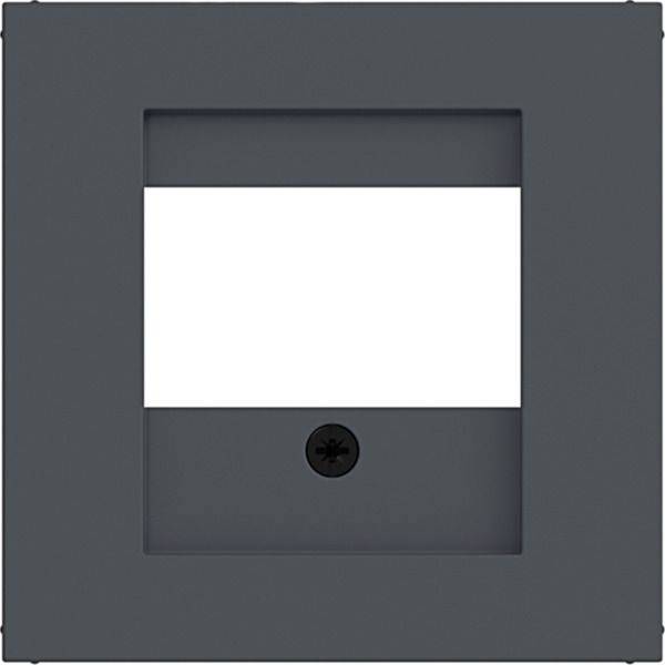Mørk grå vægplade med et centralt hvidt rektangulært panel og en lille sort cirkulær åbning under det.