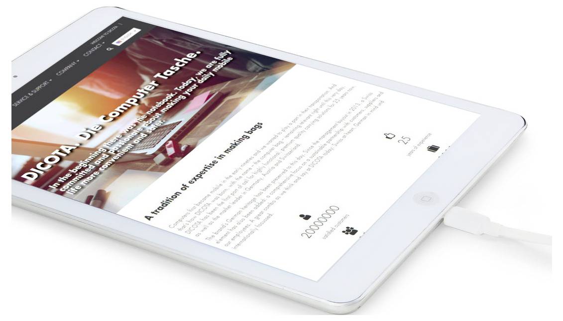 En hvid tablet, der viser en tysk nyheds-/artikelwebside med en stor overskrift og billede, vist i en vinkel mens den oplader.