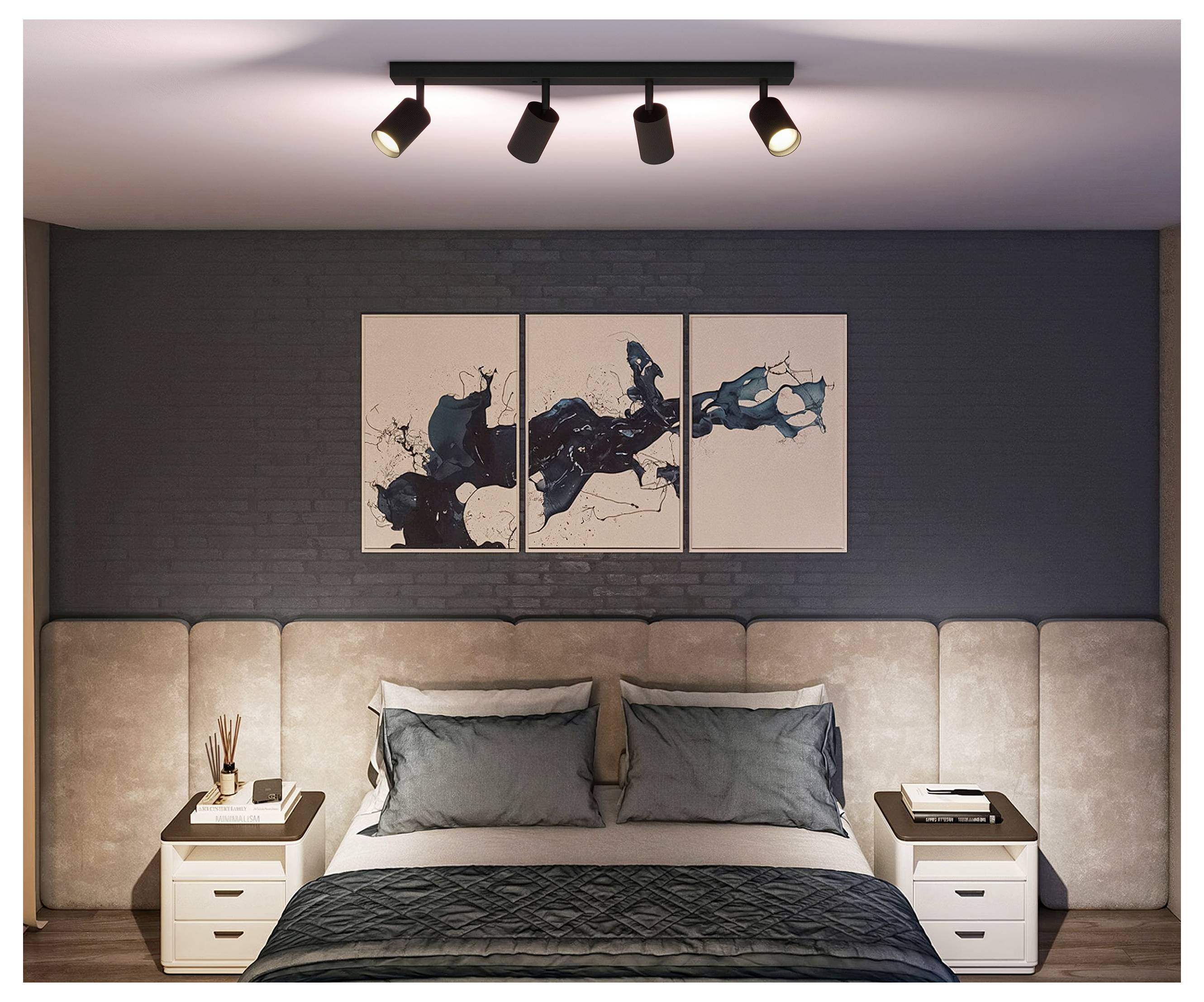 Moderne soveværelse med en pænt opgjort seng, to natborde, vægkunst over senghovedet og spotlights i loftet.