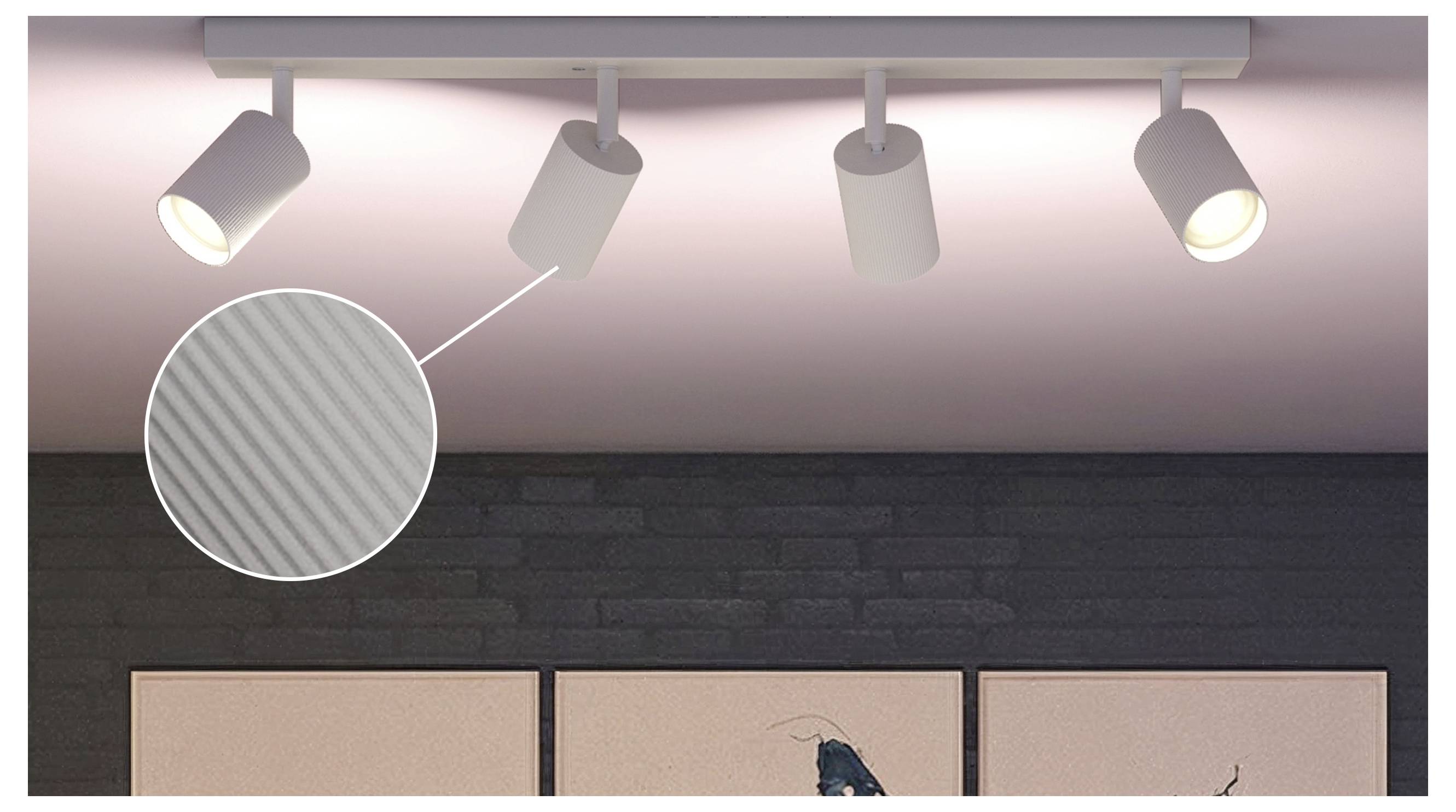 Sporbelysning på et loft med en spotlight vist i et cirkulært nærbillede, der fremhæver dens stribet tekstur mod en mørk væg og et rosalyst loft.