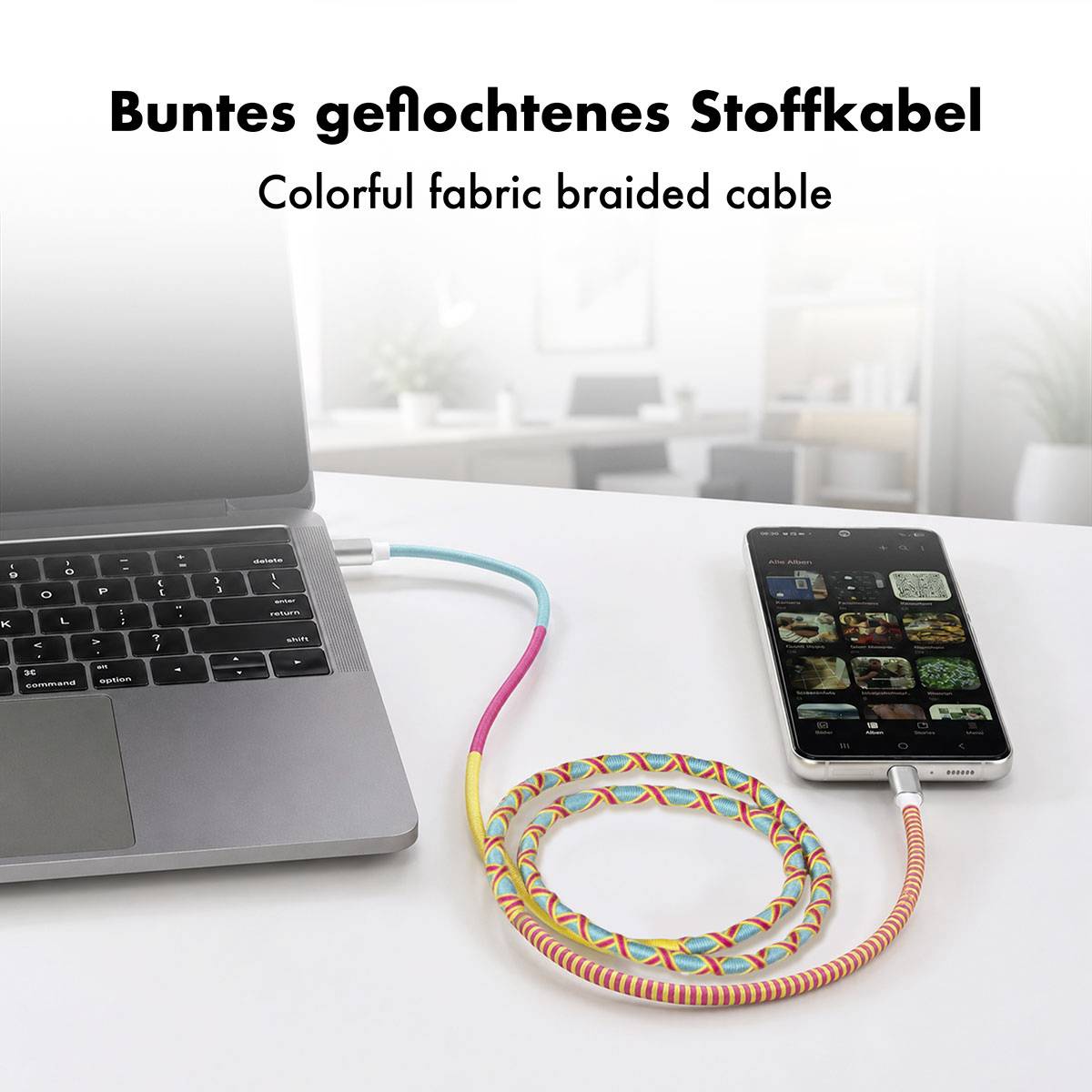 Bærbar computer og smartphone forbundet af et farverigt flettet stofkabel; teksten lyder "Buntes geflochtenes Stoffkabel" og "Colorful fabric braided cable".