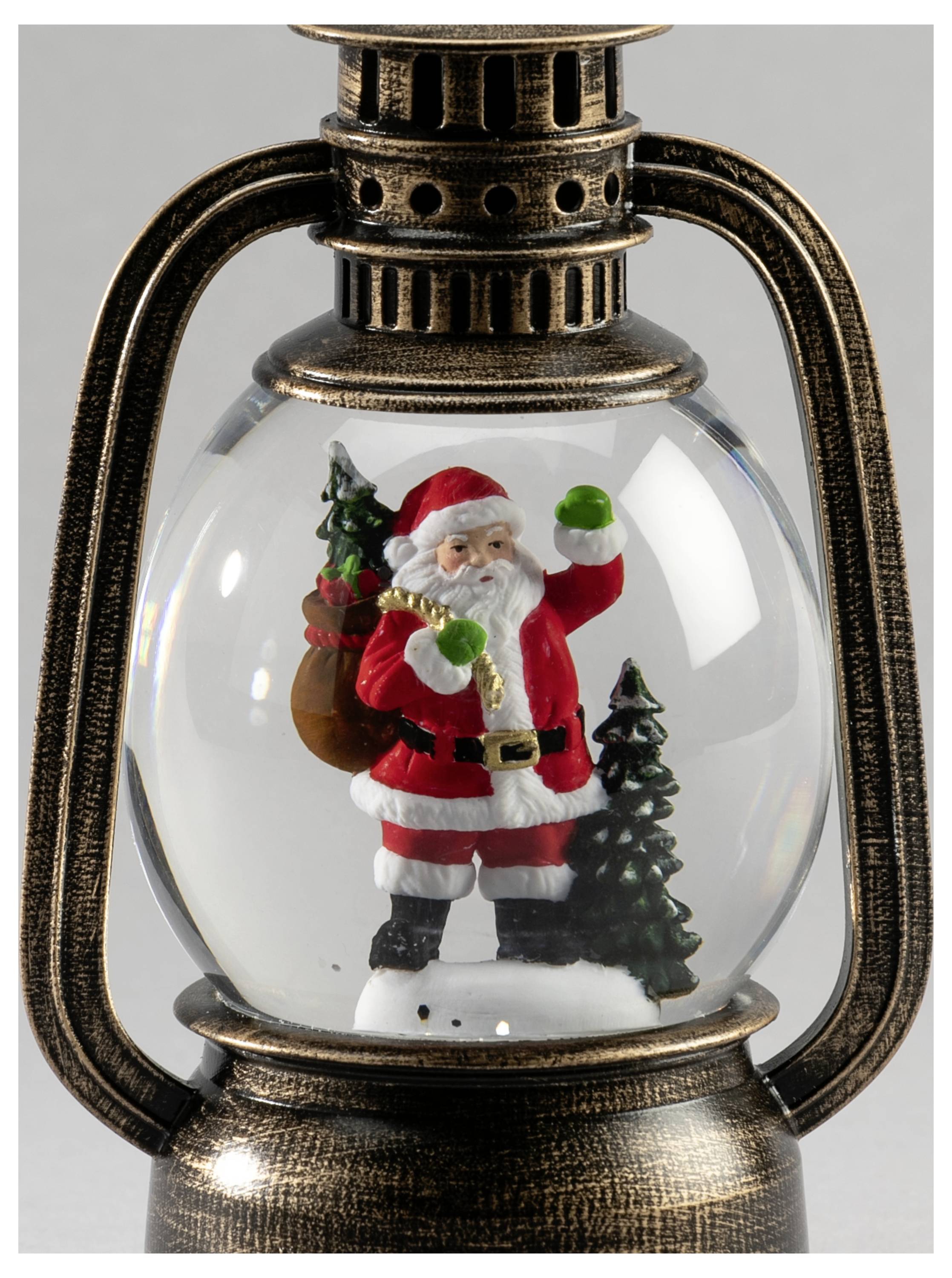 Vintage-lygte indeholdende en julemandsfigur med gavepose og juletræ inden i en klar glaskugle.