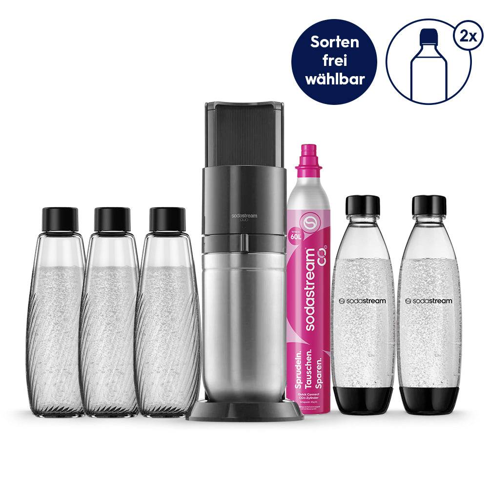 SodaStream-kultvandsmaskine med tre genanvendelige glaskleiner, en CO2-cylinder og to plasticflasker; etiketten siger "Sorten frei wählbar" og "2x".