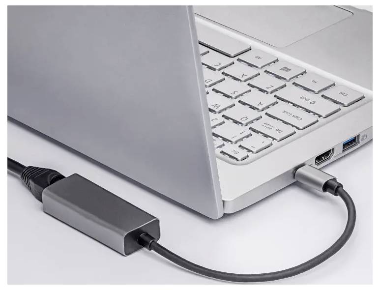 Bærbar computer forbundet til en ekstern enhed via et USB-C-adapterkabel på en hvid overflade.