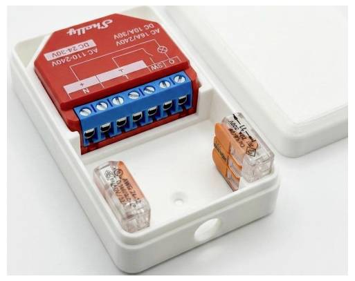 En rød og blå elektrisk klemmeblok med ledningsdiagram og to klare orange-farvede stik inden i et hvidt plastikhuus.