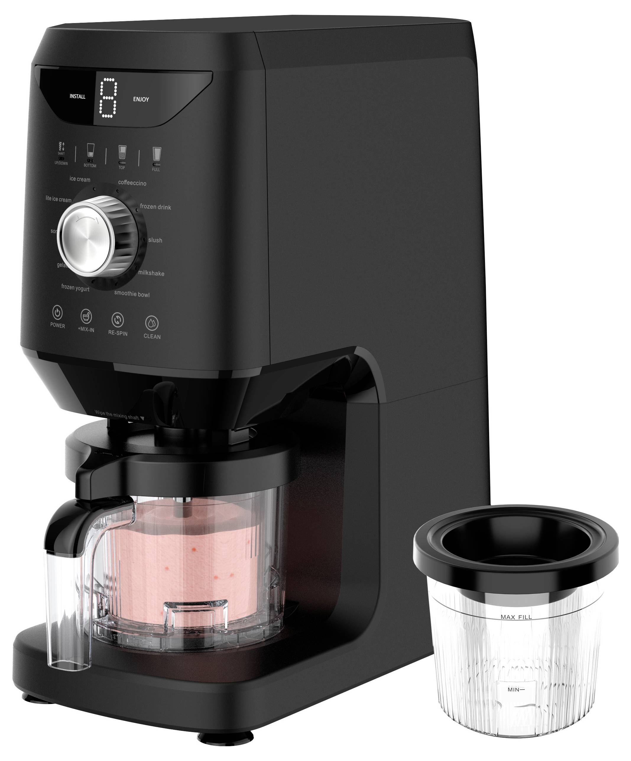 Sort kaffemaskine med digitalt display og kontroldrejeskive, vist bryggende i en glaskande; en målefilter-kurv ligger ved siden af den.
