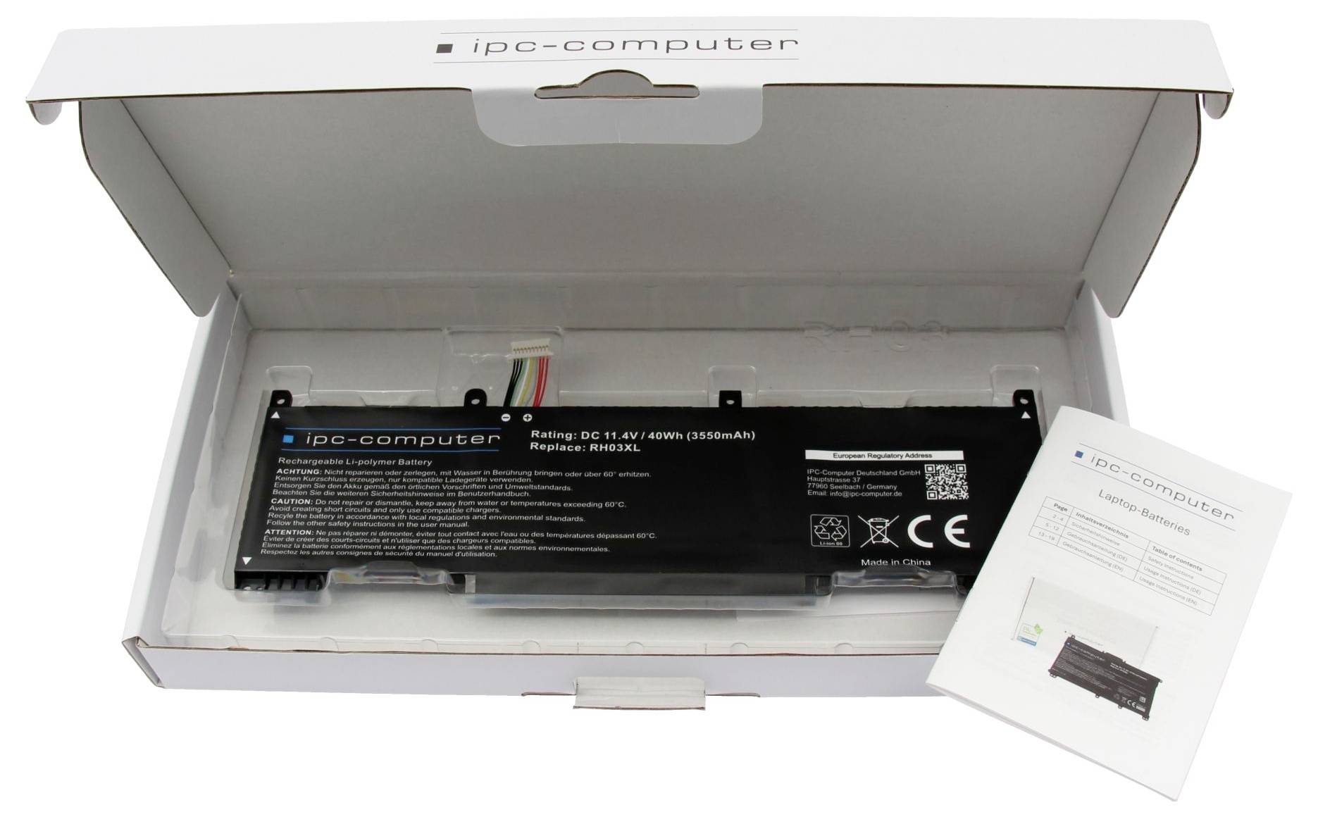 Åbn hvid 'ipg-computer' boks indeholdende et sort genopladeligt batteri og en brugervejledning