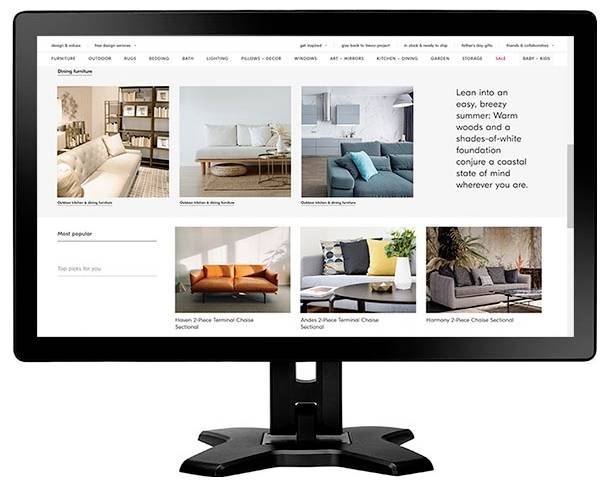 Skrivebordsskærm viser et møbelindkøbswebsted med et inspirationsgitter til stuehjørnet, sofaproduktfoto og en promobeskeds om en varm sommerstil.