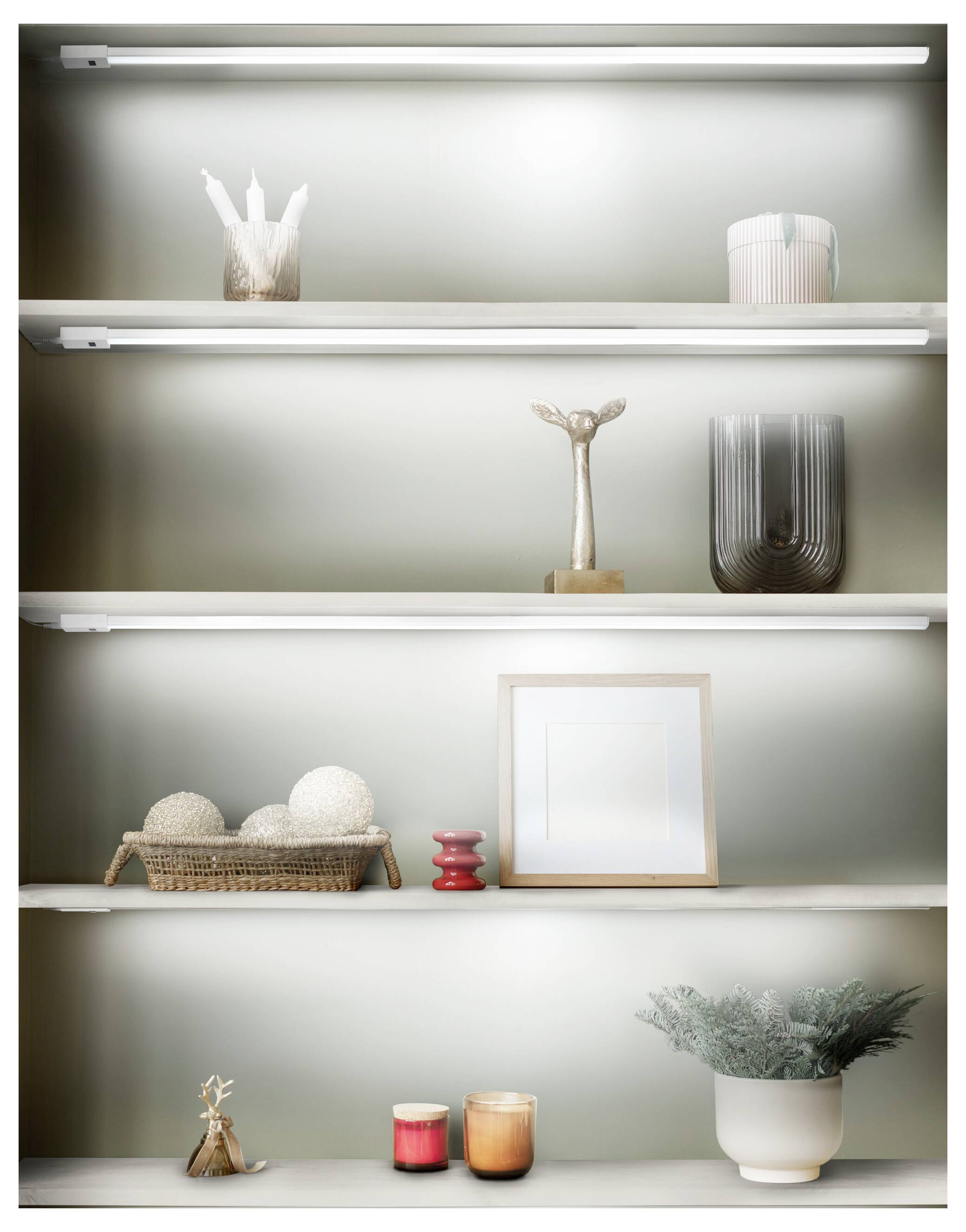 Oplysdte vægskabe, der viser minimalistisk dekoration: vaser, skulptur, indrammet kunst, stearinlys, en vævet kurv og en pottet plante.