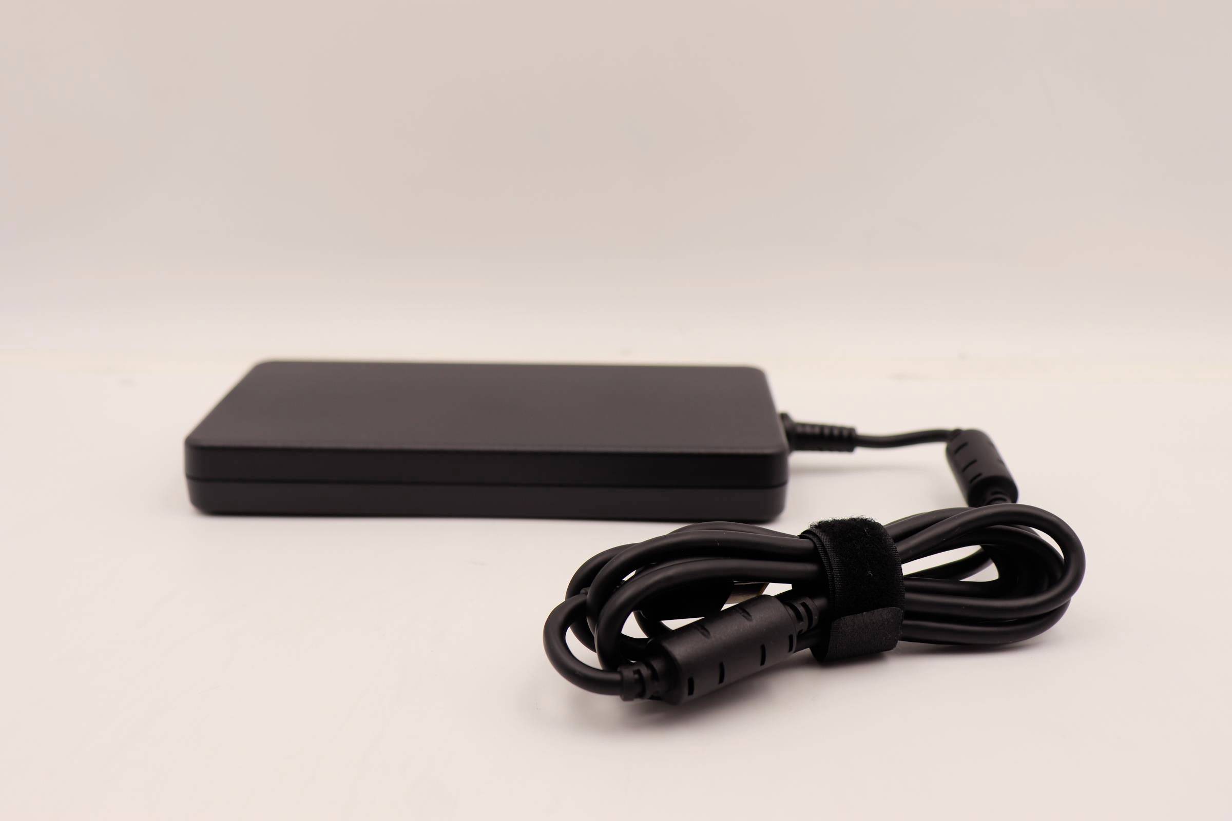 Sort bærbar computer strømadapter med medfølgende kabel og snoet ledning på en plain hvid baggrund.