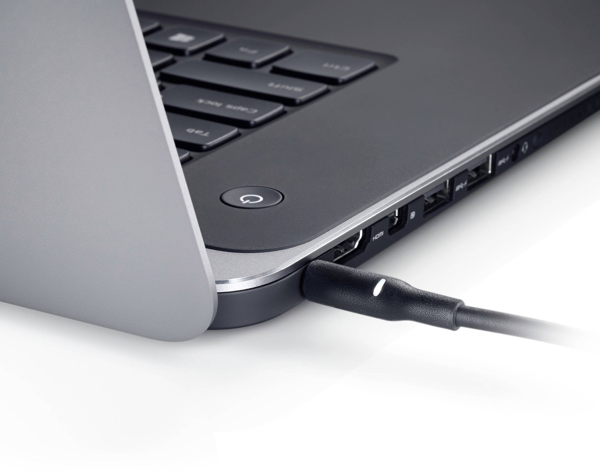 Nærbillede af en laptopkant med et kabel tilsluttet en USB-port ved siden af tændknappen.