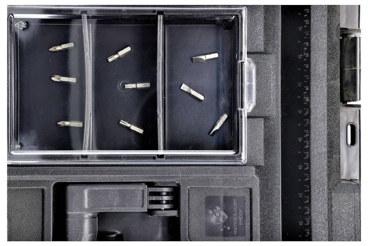 Åben kasse med seks små metaldele organiseret i tre rum og et sort måleinstrument med en linealmålepind langs højre side.