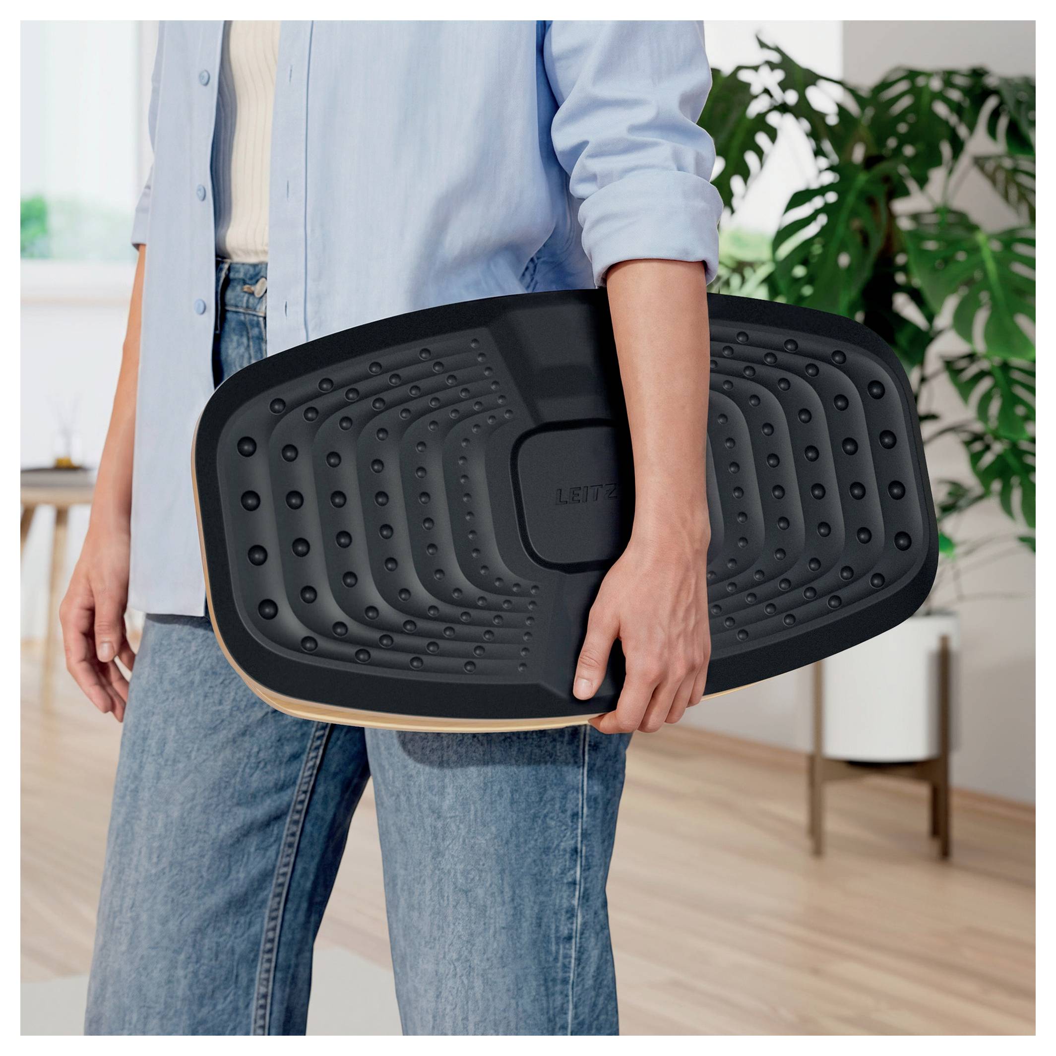 Person, der holder et sort ergonomisk balancebræt indendørs.