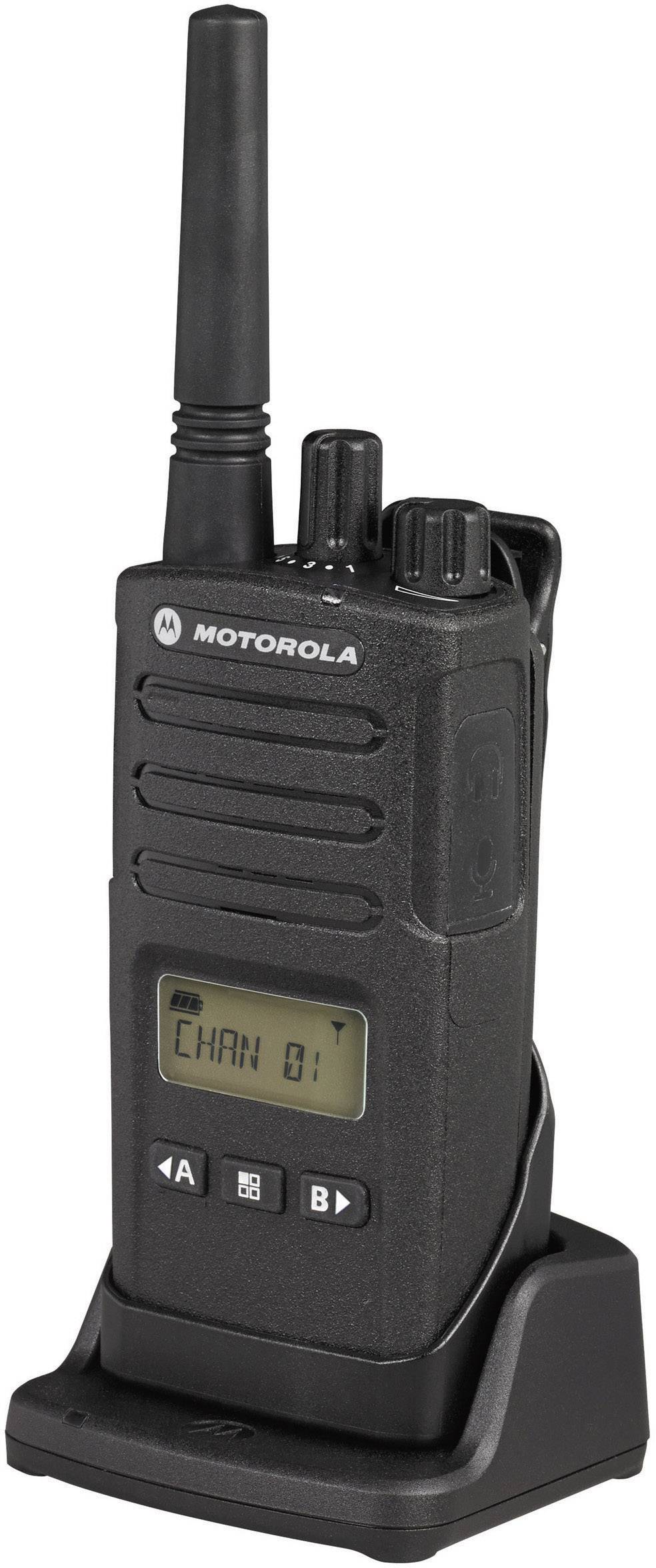 Et sort Motorola-håndradio med antenne og display viser 'KANAL 01'. Den står i en oplader.