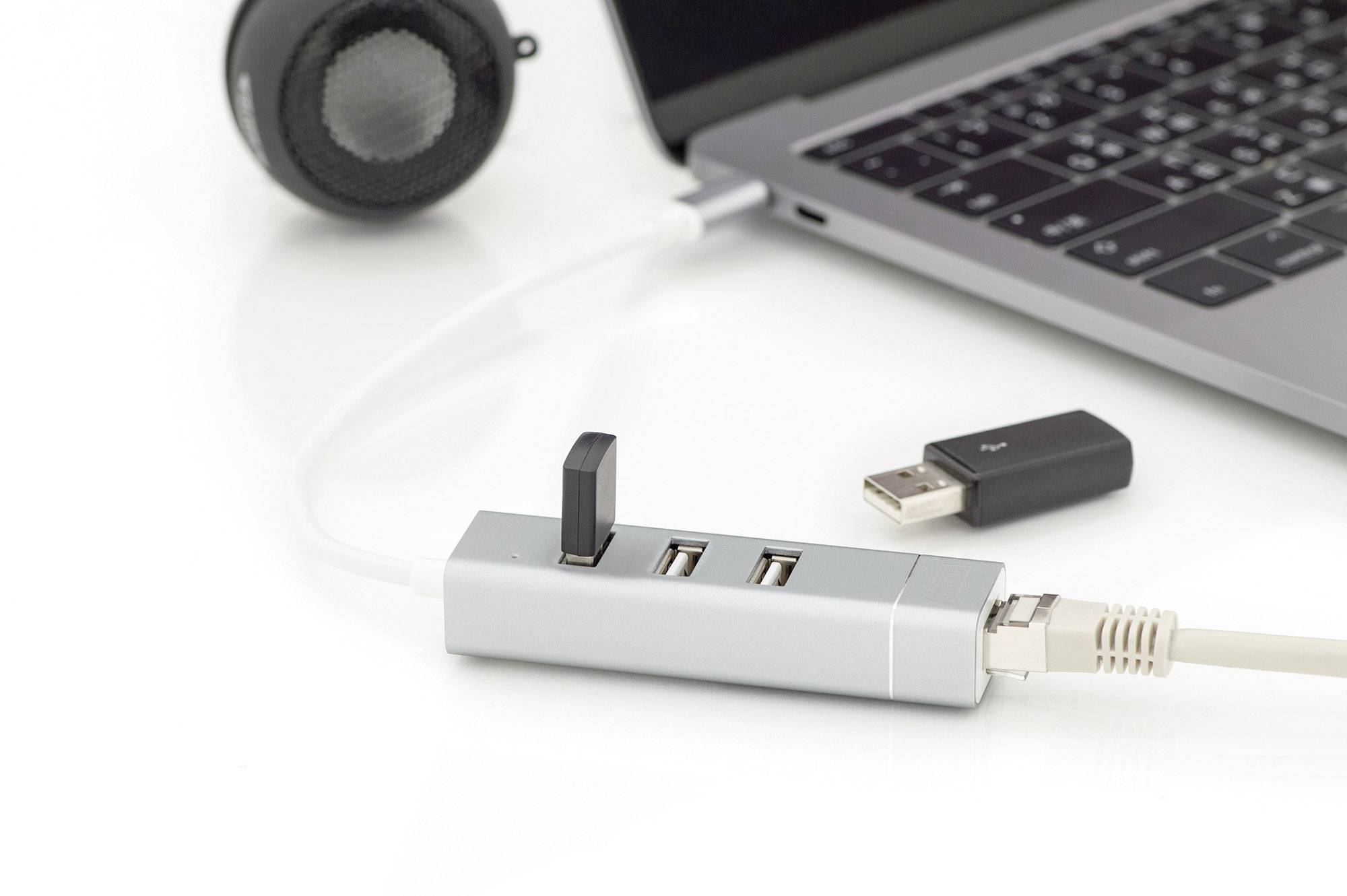 Bærbar computer forbundet med en netværksadapter via USB, viser også højttalere og USB-stik. Fokus på konnektivitet og tilbehør.