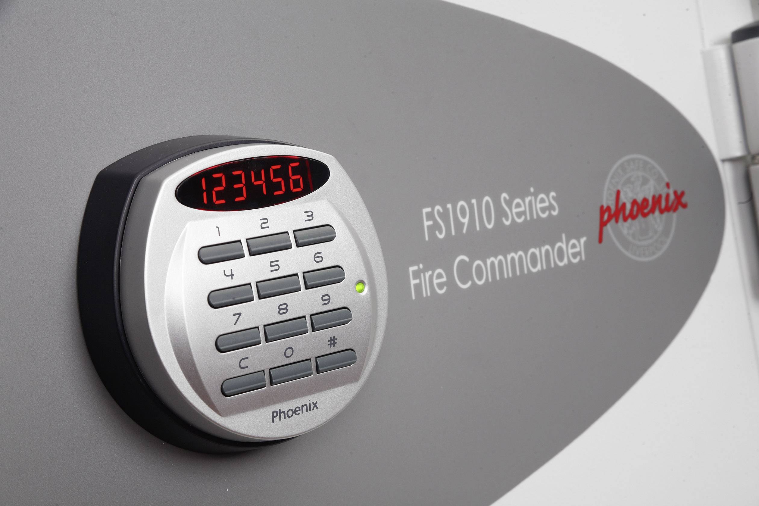 Et elektronisk talllås på en pengeskab med påskriften 'FS1910 Series Fire Commander'. Displayet viser '123456'.