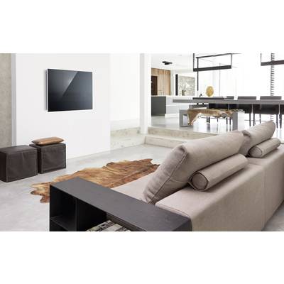 Moderne stue med beige sofa, vægmonteret fjernsyn og tæppe. Åbent køkken i baggrunden. Elegant, minimalistisk design.