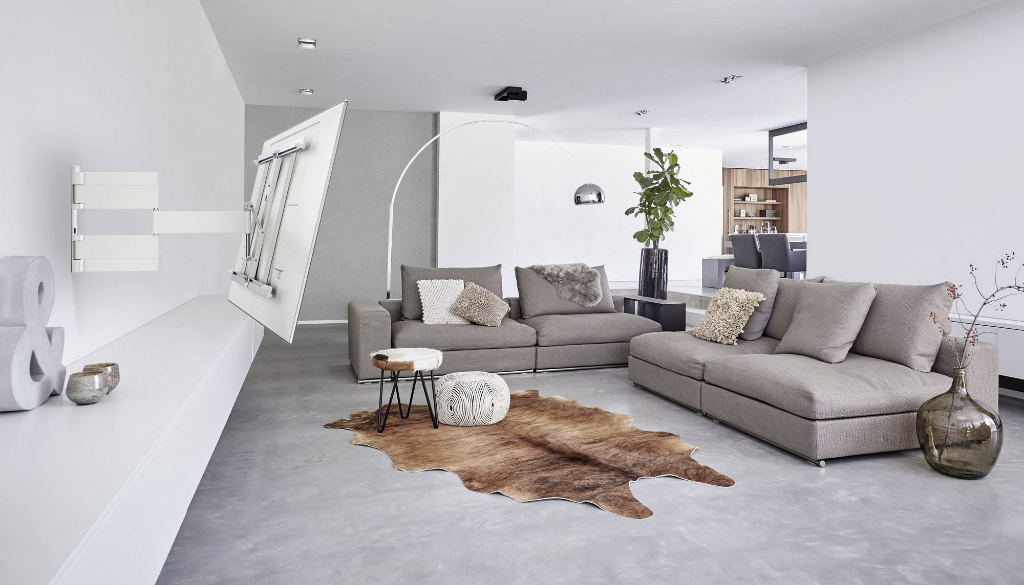 Et moderne indrettet stue med to grå sofaer, en justerbar vægmonteret fladskærm og et tæppe i dyrehudsdesign.