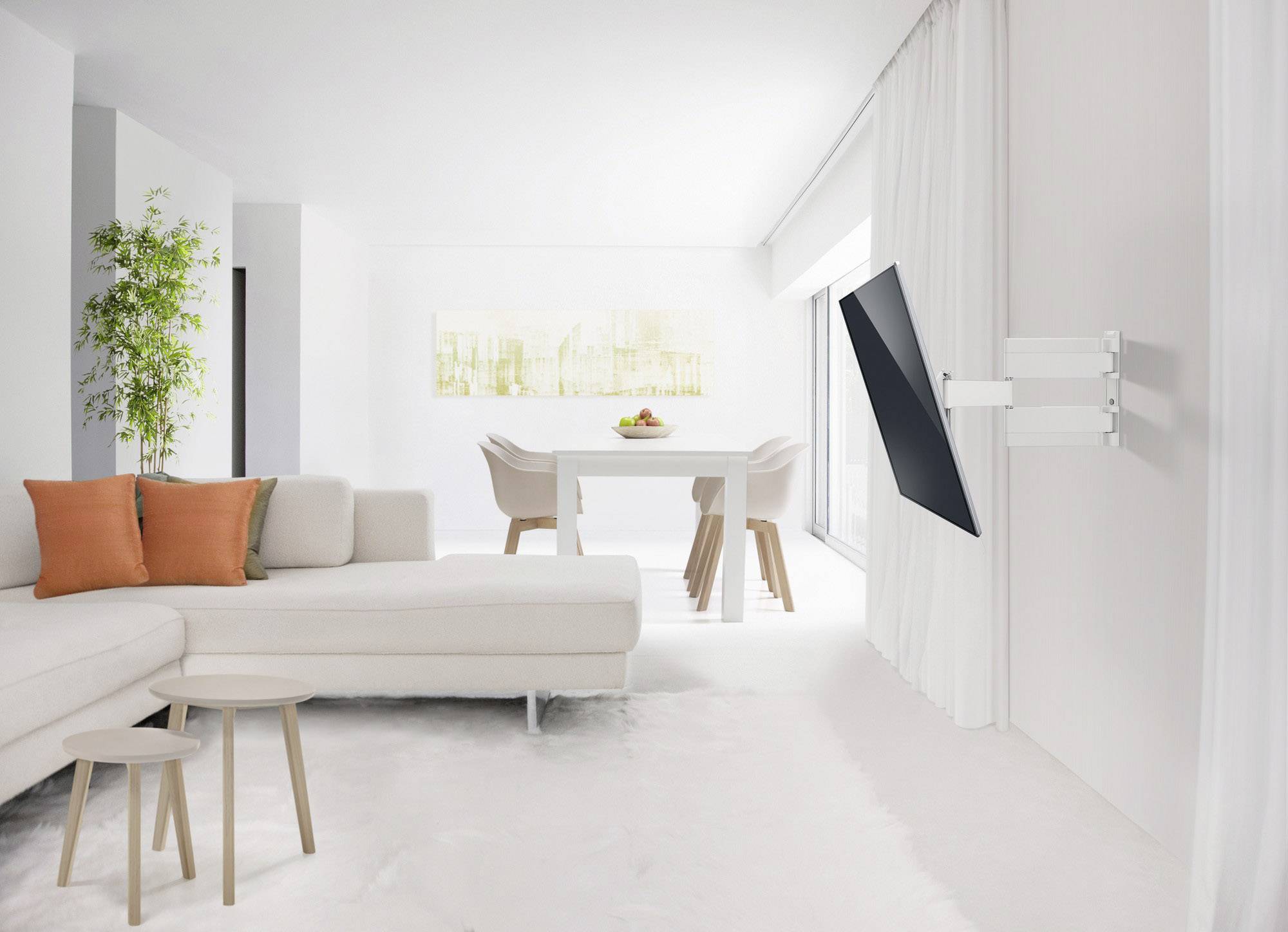 Lyst, moderne stue med hvid sofa, orange puder, to små borde i træ, vægmonteret fjernsyn og et spisebord med fire stole.