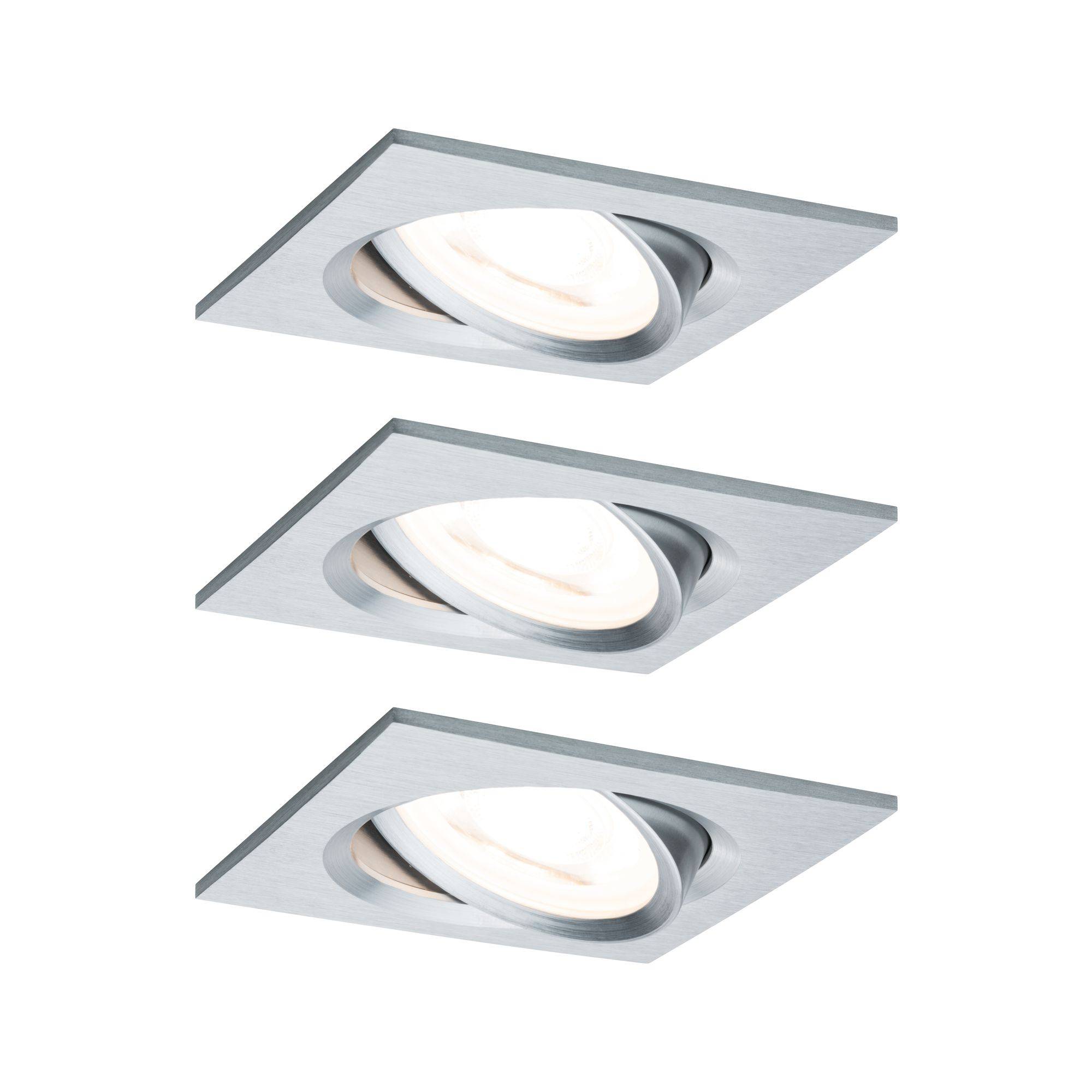 Tre kvadratiske indbygningsspots i børstet metalfinish er arrangeret i en skrå linje. De udsender et varmt lys.