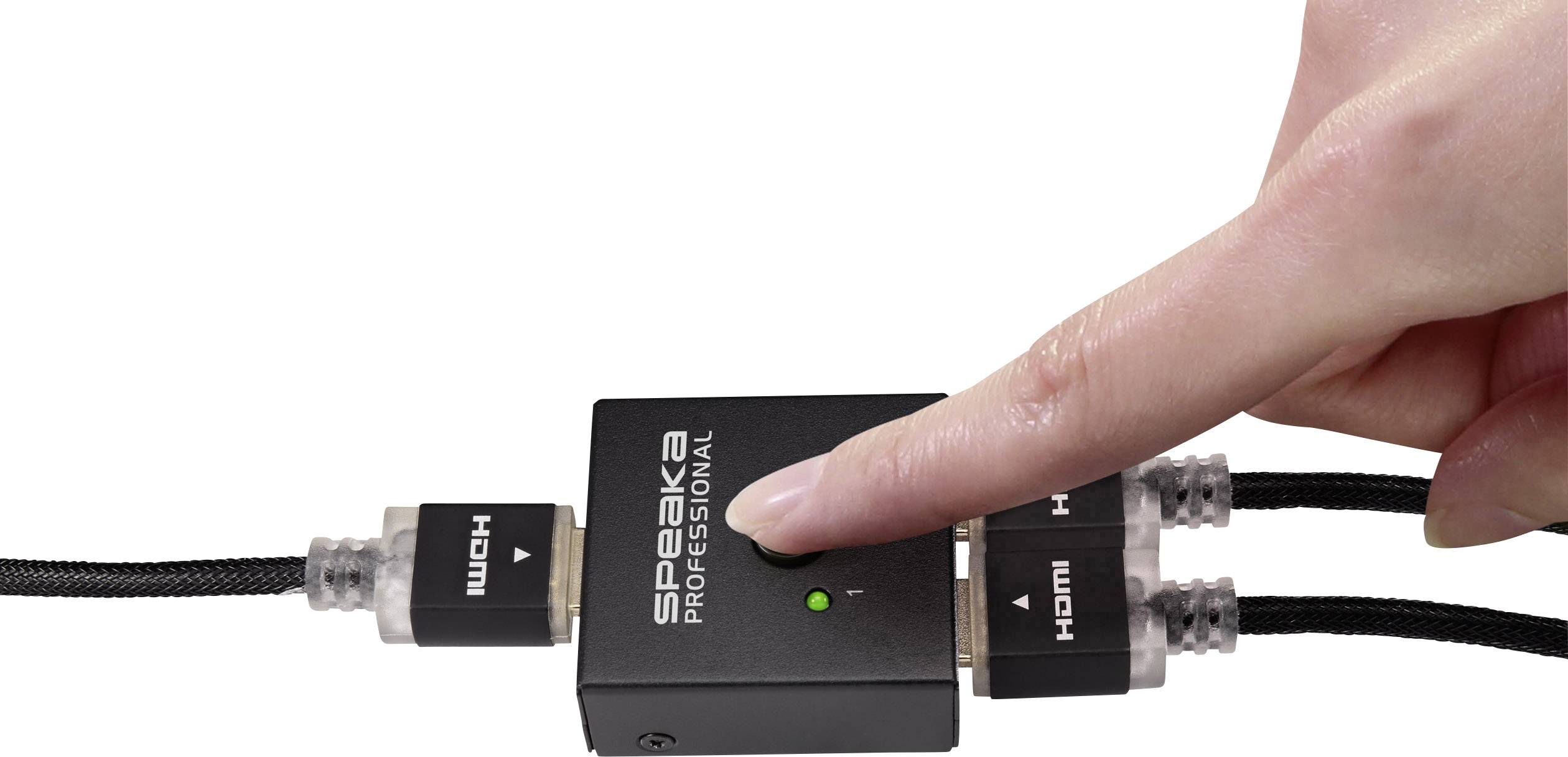 En hånd trykker på knappen på en sort HDMI-splitter fra mærket 'SpeaKa Professional', som forbinder to HDMI-kabler.