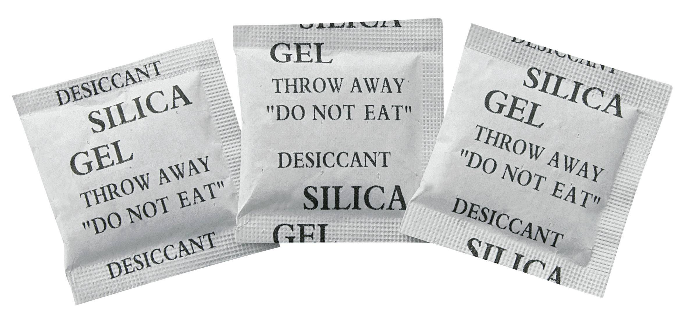 Tre silica gel-poser med påtrykt 'Desiccant' og 'Smid væk, må ikke spises'. Bruges til fugtabsorption i emballager.