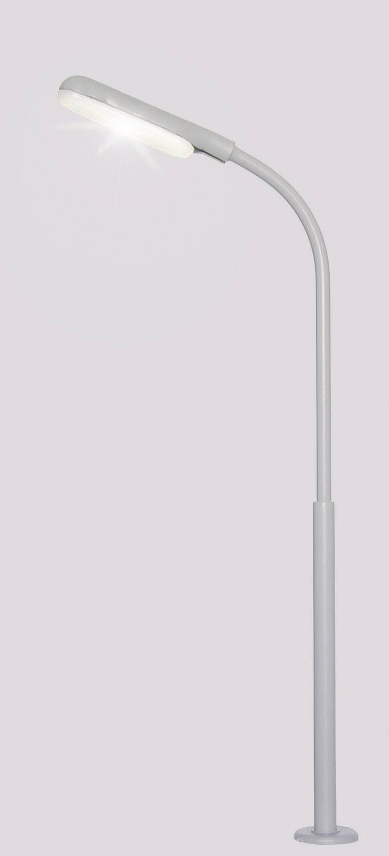 Grå, moderne standerlampe med bøjet arm, som kaster et skarpt lys nedad.