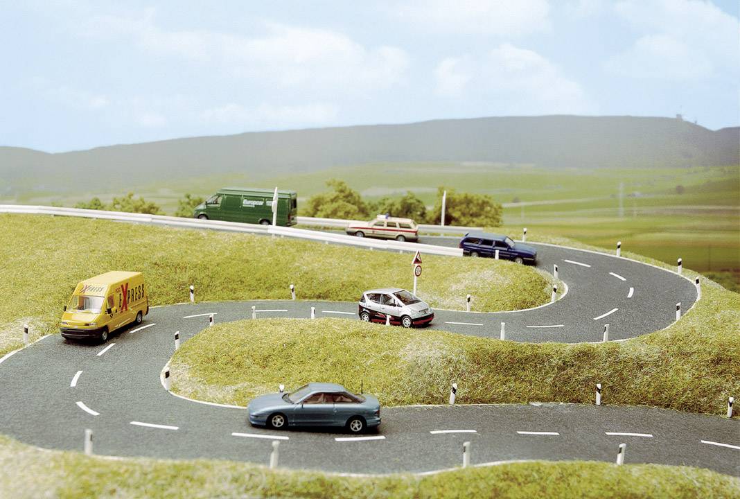 Snoet vej i landlig landskab med modelkøretøjer, der repræsenterer forskellige køretøjstyper.