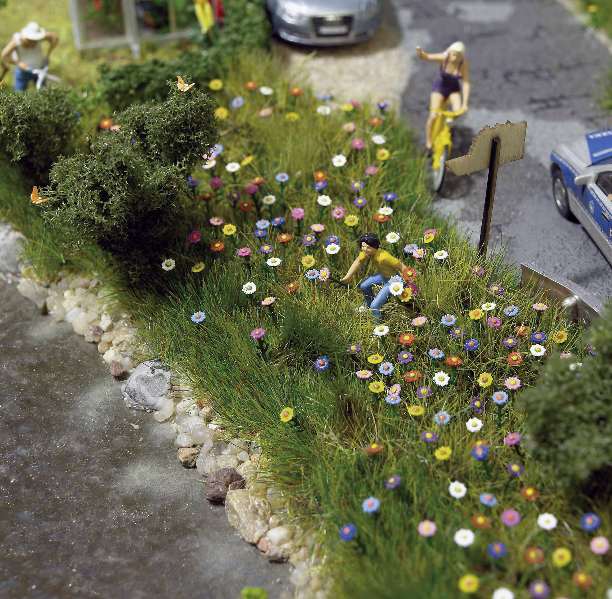 To miniature figurer planter blomster langs en sti. En bil og en person ses i baggrunden.