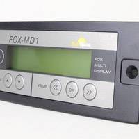Billedet viser en digital displayenhed med påskriften 'FOX-MD1'. Den har knapper til forskellige funktioner, sandsynligvis til styring af enheden.