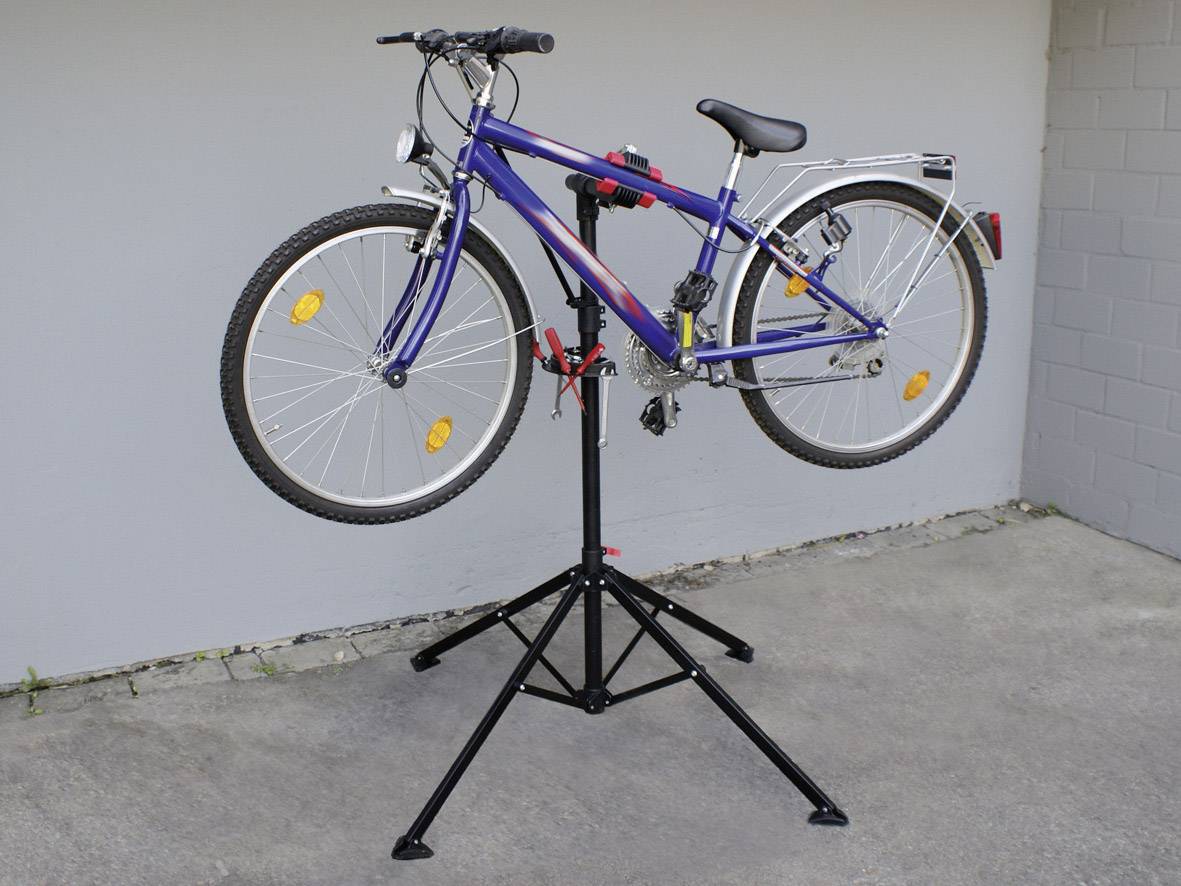En blå cykel er monteret på en sort reparationsstativ. Stativet holder cyklen stabilt under vedligeholdelsesarbejde.