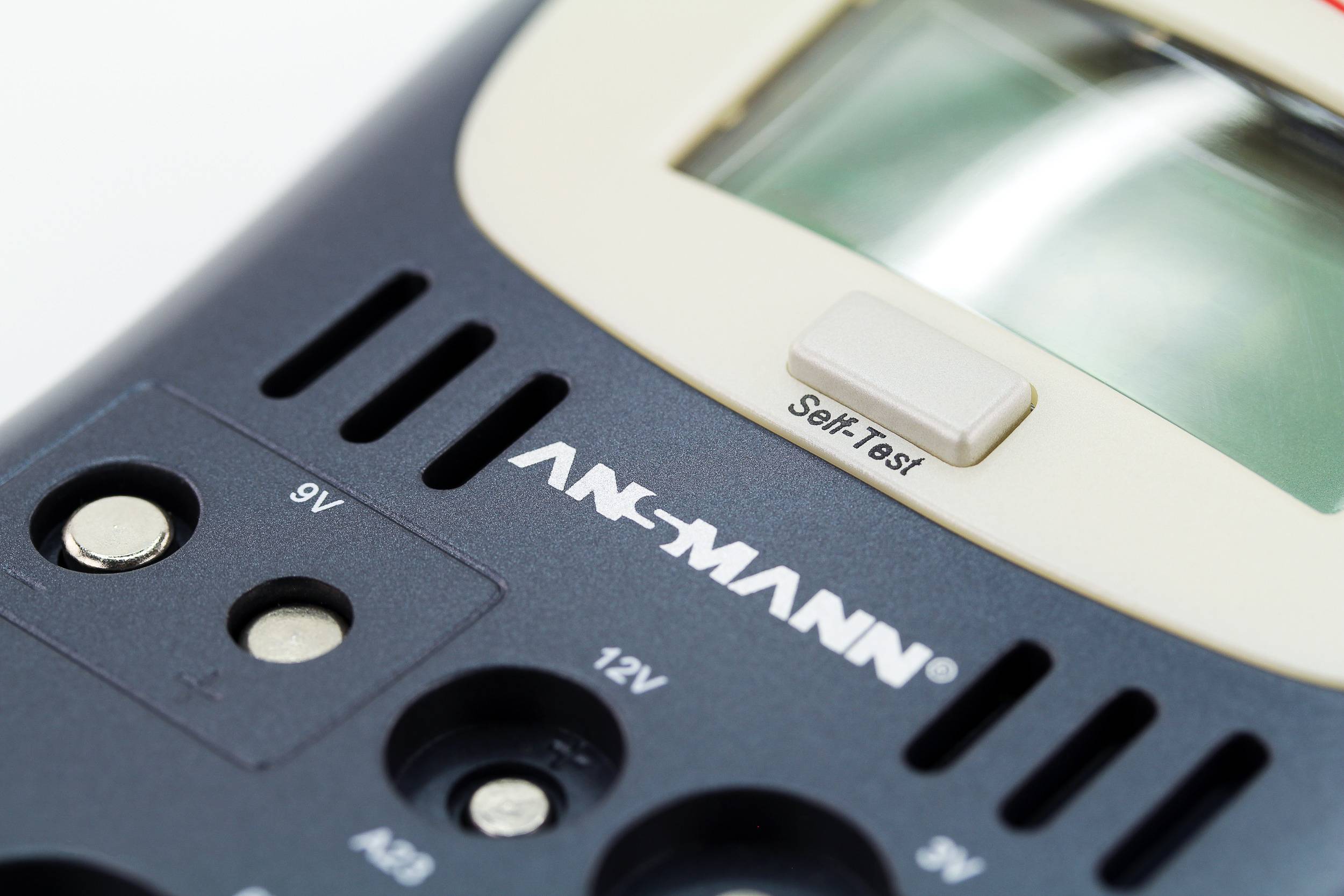 Ein Batterietester mit Anzeige für verschiedene Batterietypen. Ein Knopf ist mit 'Self Test' beschriftet, Markenname sichtbar.