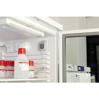 Ein geöffneter Kühlschrank mit Plastikflaschen, teils beschriftet. Ein Thermometer zeigt 21 Grad Celsius. Umgebung scheint ein Labor zu sein.