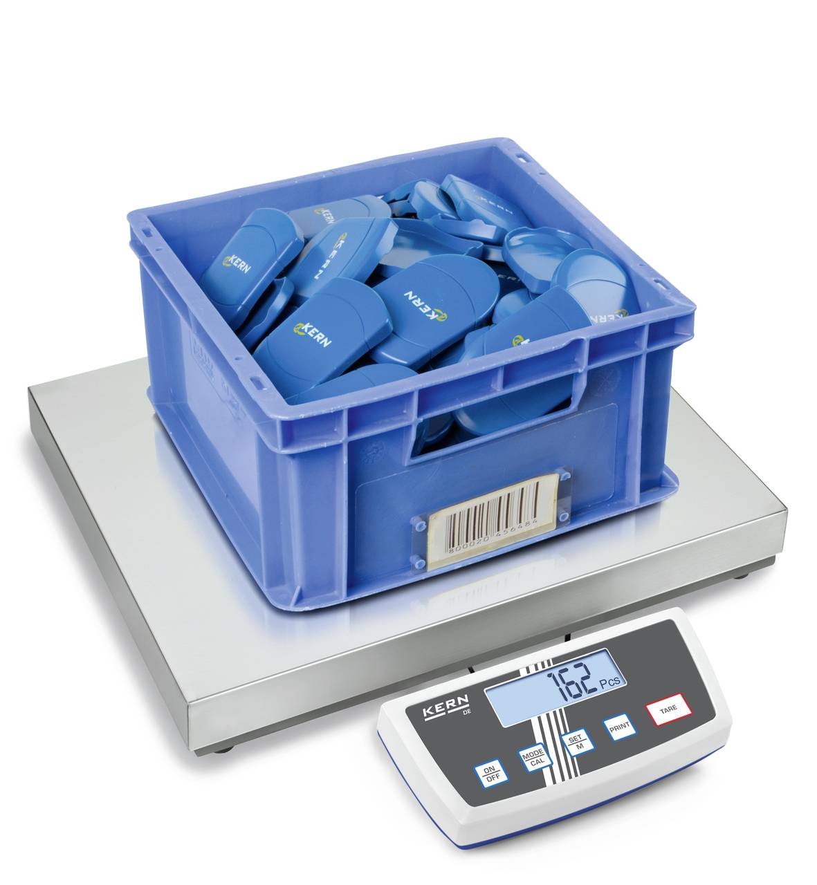 Eine blaue Kunststoffkiste voller blauer Objekte steht auf einer elektronischen Waage. Das Display zeigt ein Gewicht von 7,62 kg an.
