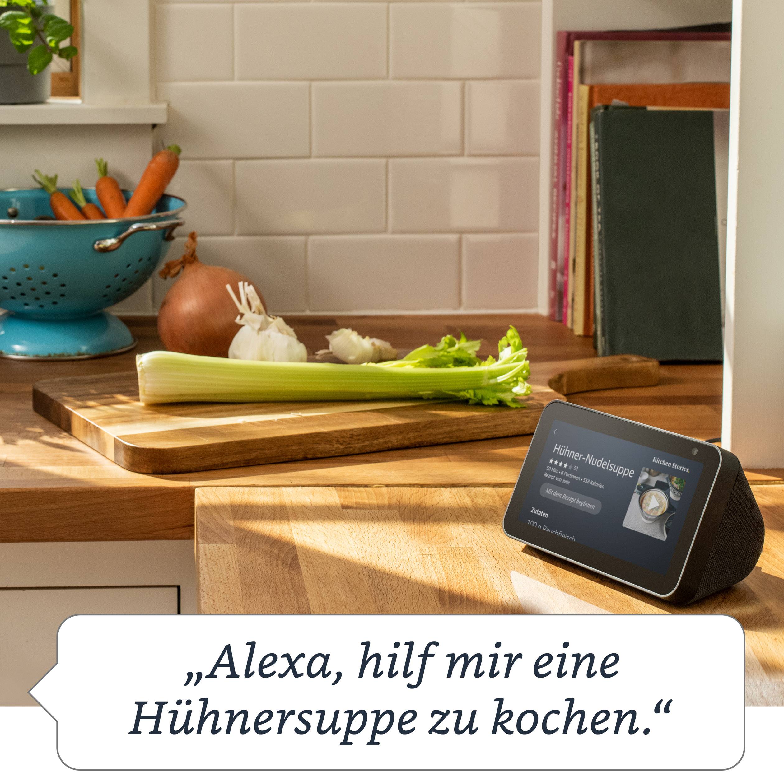 Das Bild zeigt eine Küche mit Gemüse auf einem Schneidebrett. Ein Smart Display zeigt das Rezept 'Hühnersuppe'.