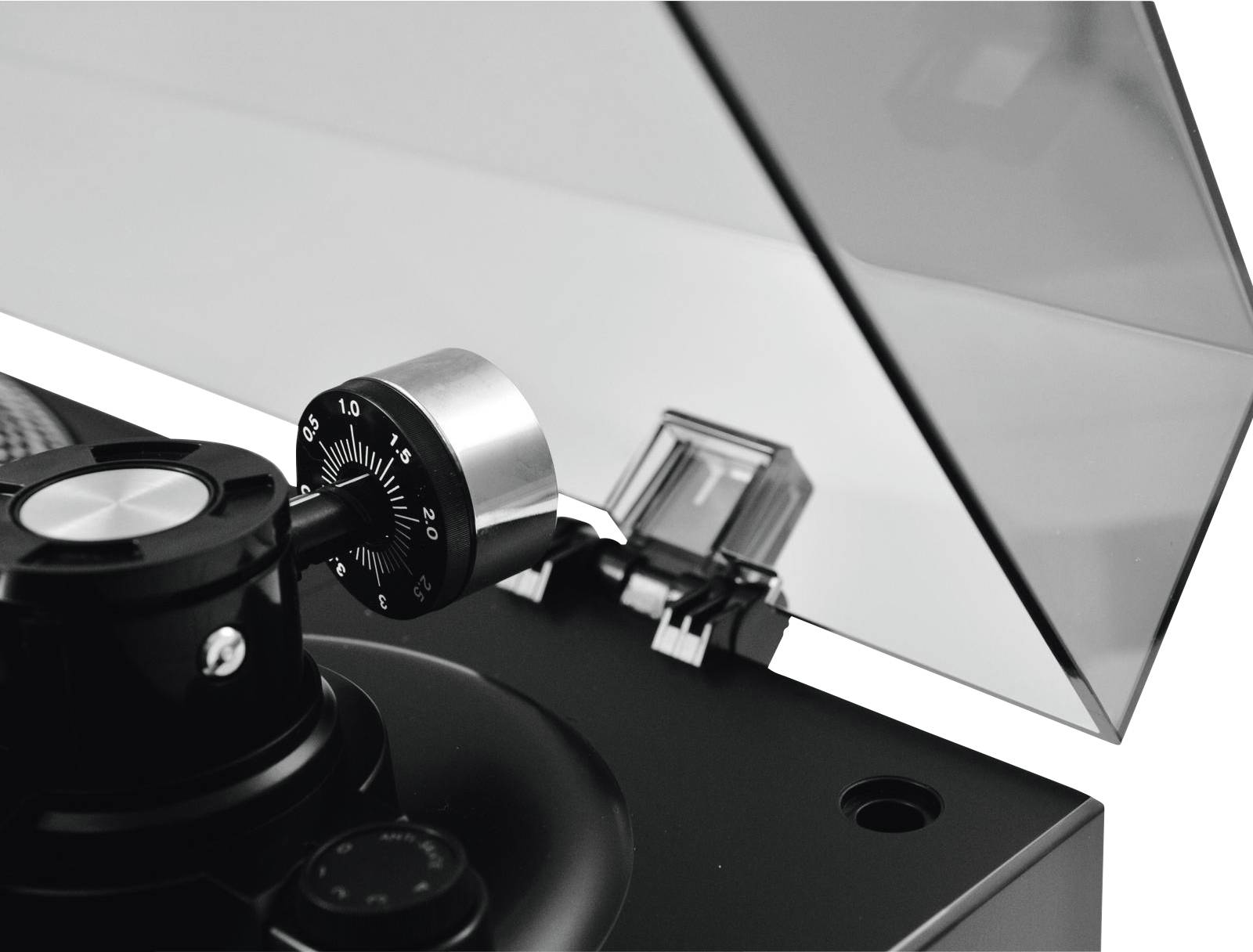 Ein schwarzer Plattenspieler mit geöffnetem transparentem Deckel. Nahaufnahme des Tonarms, fokussiert auf die Einstellskala.