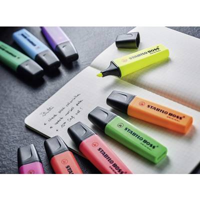 Mehrfarbige Textmarker und ein geöffnetes Notizbuch mit handschriftlichen Notizen auf schwarzem Hintergrund.