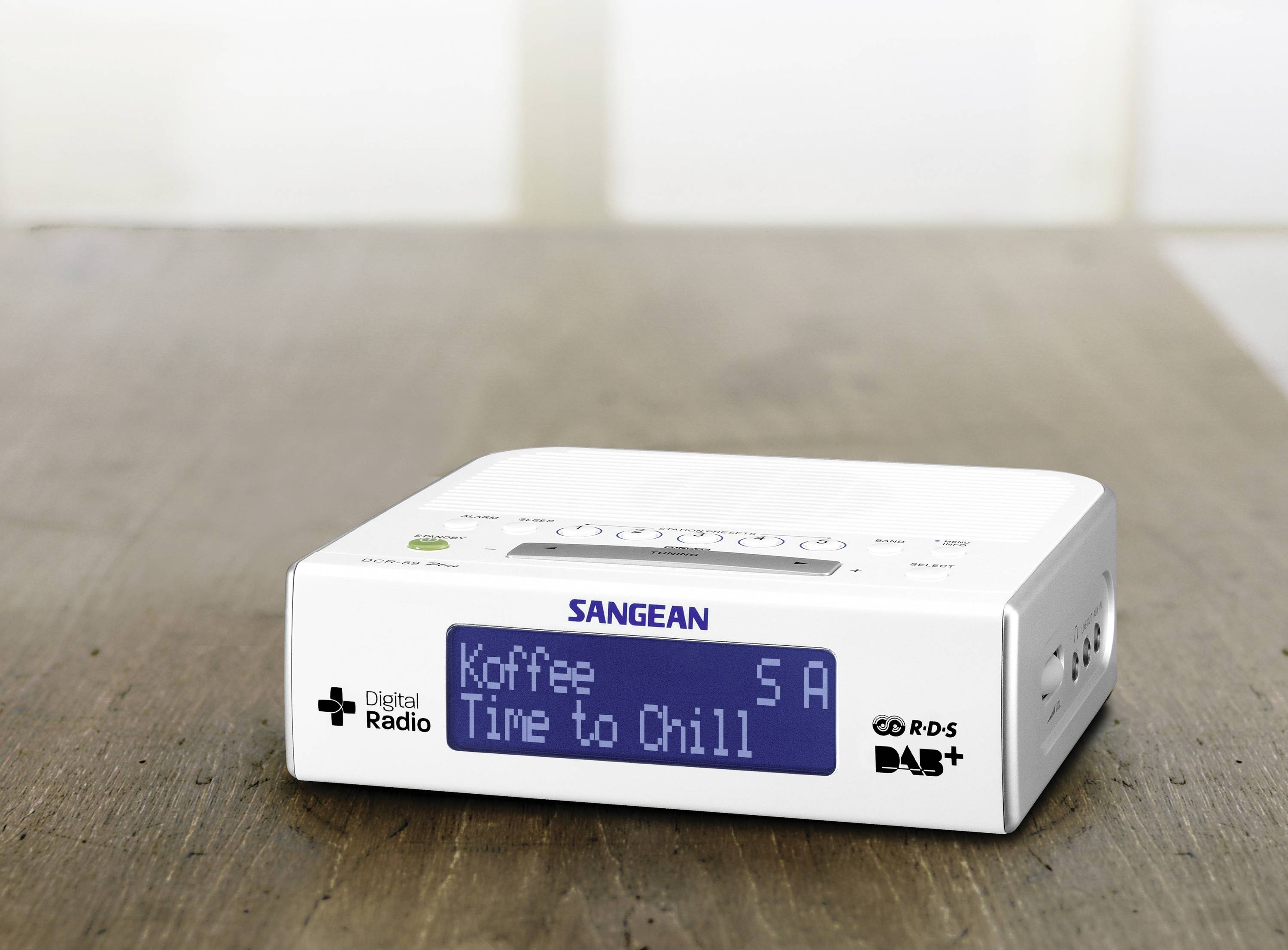 Ruhige Innenaufnahme eines Digitalradios auf einem Holztisch. Auf dem Display stehen die Worte 'Koffee Time to Chill'.