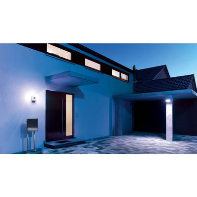 Einfamilienhaus bei Dämmerung, moderne Architektur mit flachem Dach, beleuchteter Eingang und Carport, blaue Beleuchtung umgeben.
