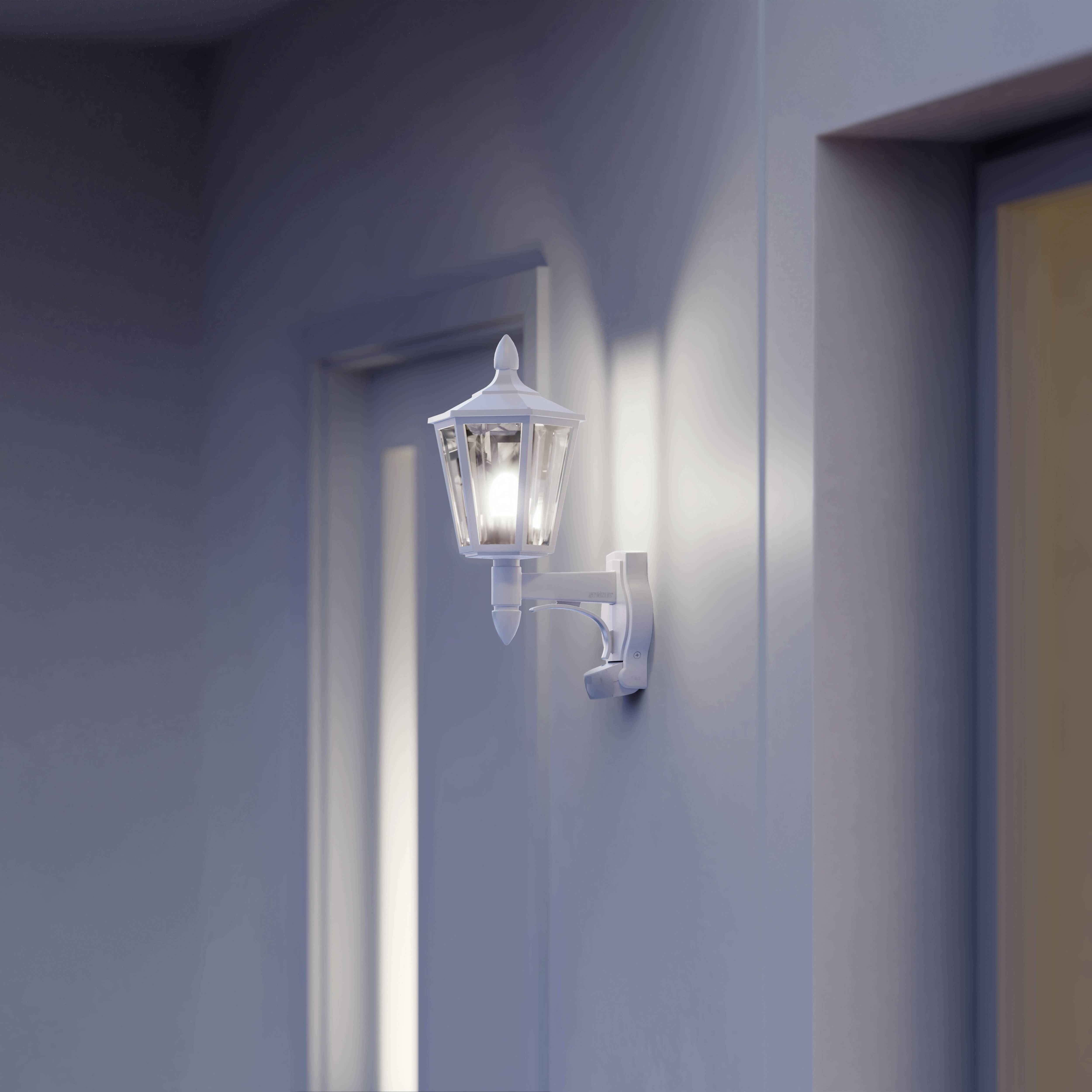 Außenlaterne an einer Wand, die sanftes Licht spendet. Das Licht beleuchtet den Bereich um eine Tür, was für Sicherheit sorgt.