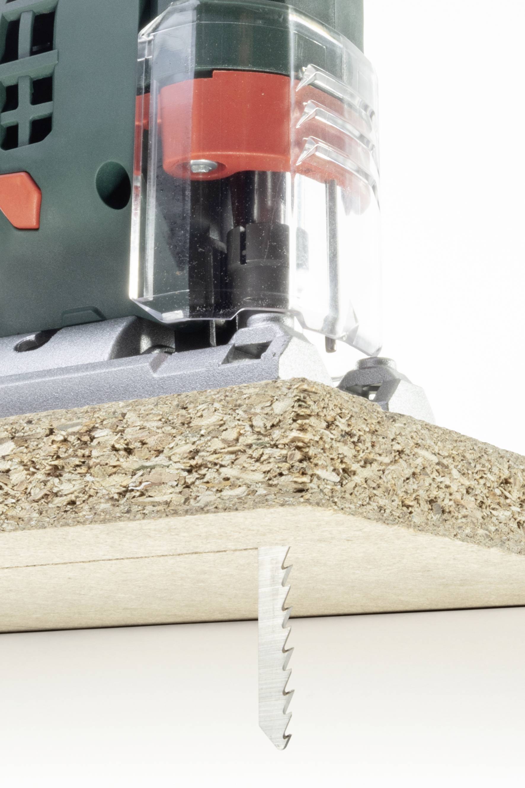 Stichsäge schneidet durch Spanplatte von unten. Sägeblatt ist sichtbar, konzentriert auf die präzise Schnittführung durch das Holz.