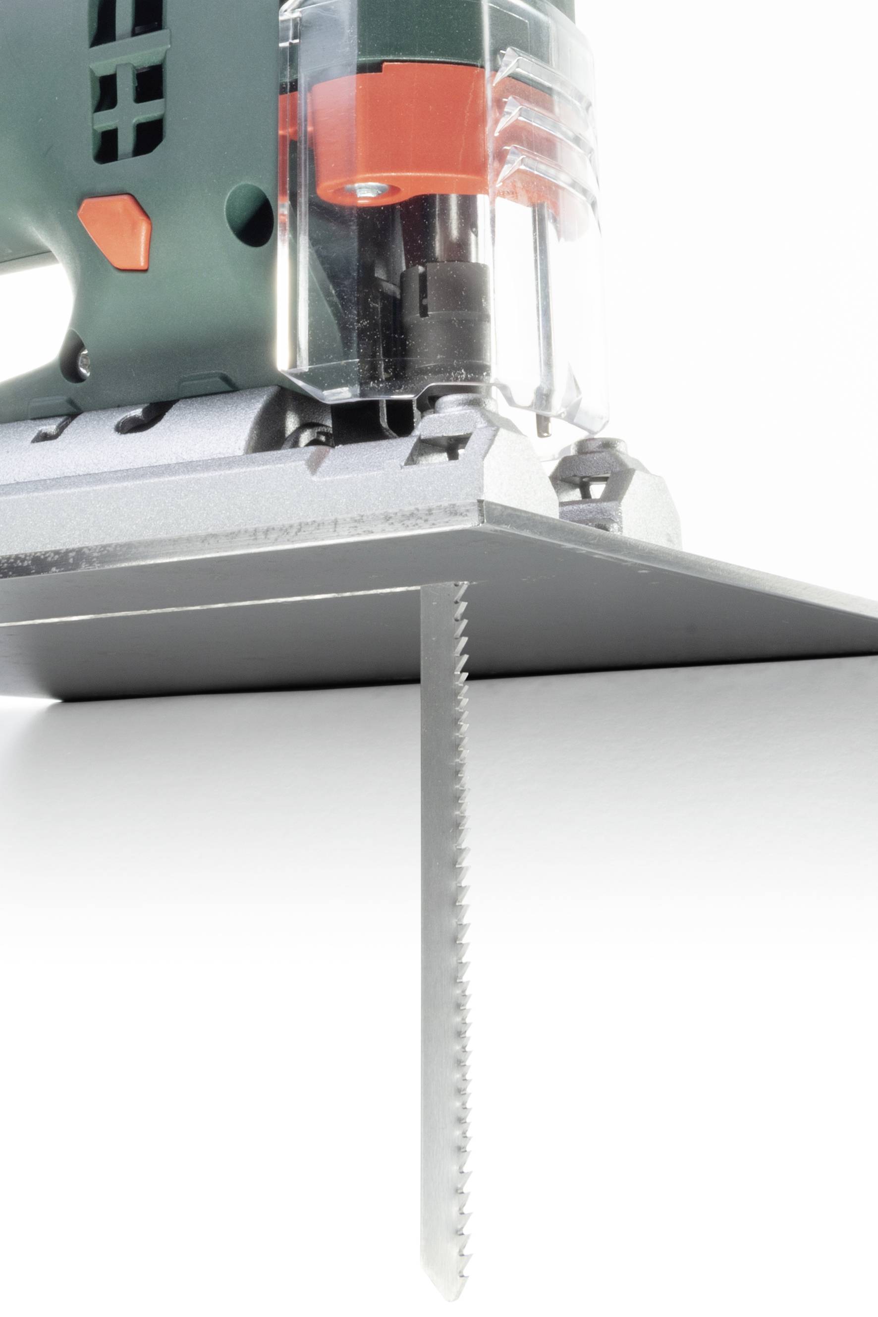 Eine elektrische Stichsäge schneidet präzise durch ein dünnes Metallblech. Die Säge ist grün und hat orangefarbene Akzente.