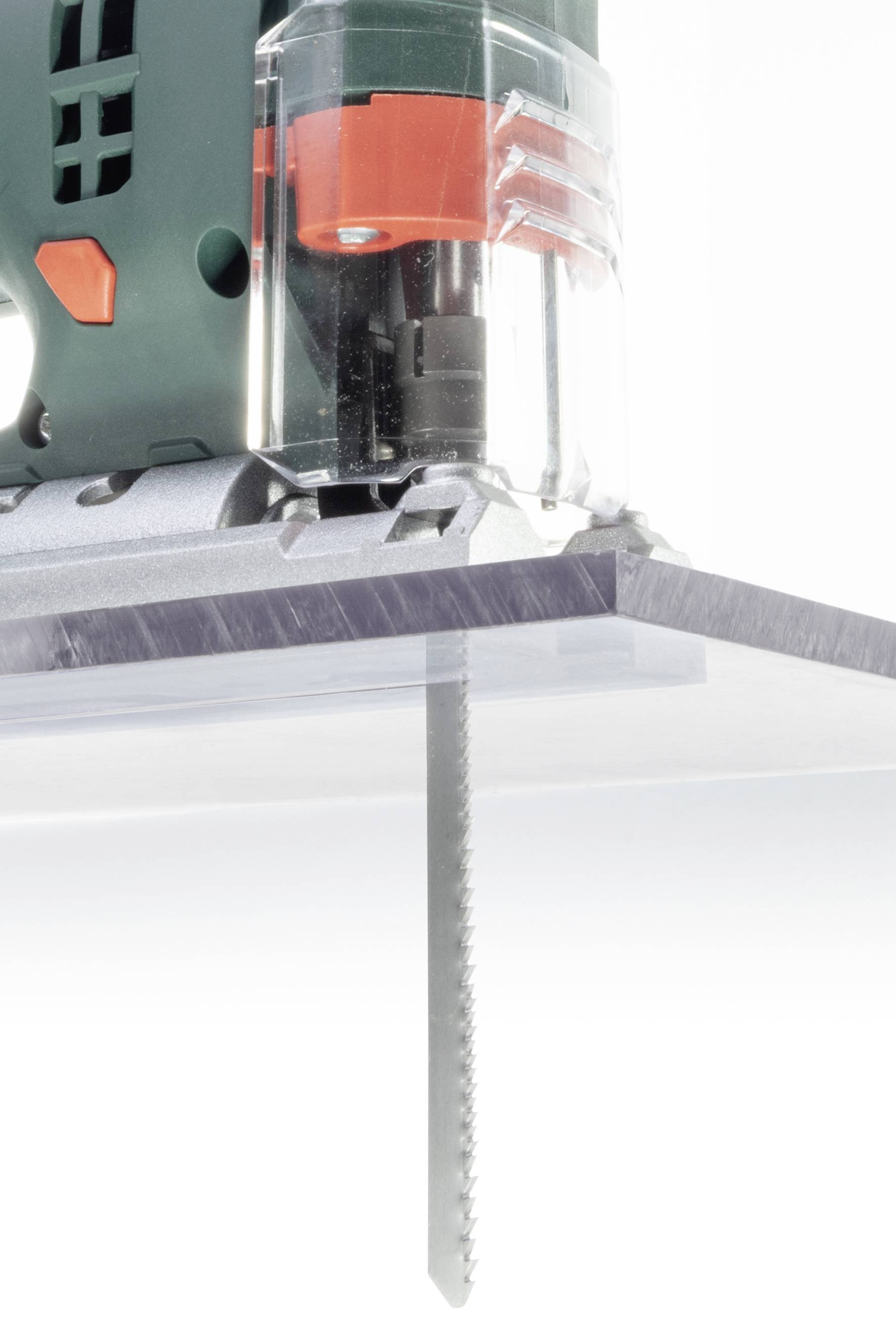 'Nahaufnahme einer Stichsäge, die ein Stück Plexiglas von oben nach unten sägt. Die Sägeblätter bewegen sich durch das Material.'