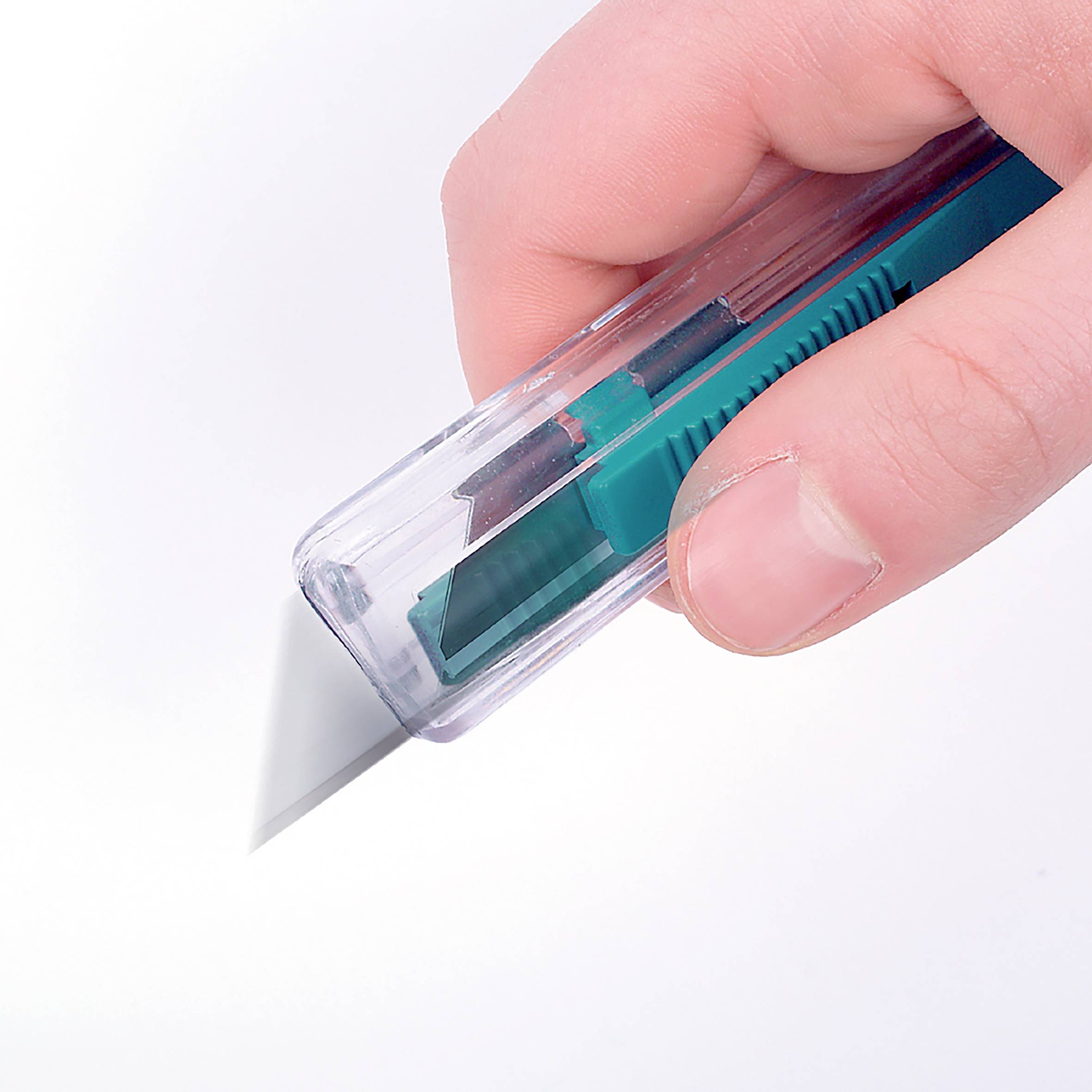 Ein grünes Teppichmesser in einer Hand schneidet Papier.