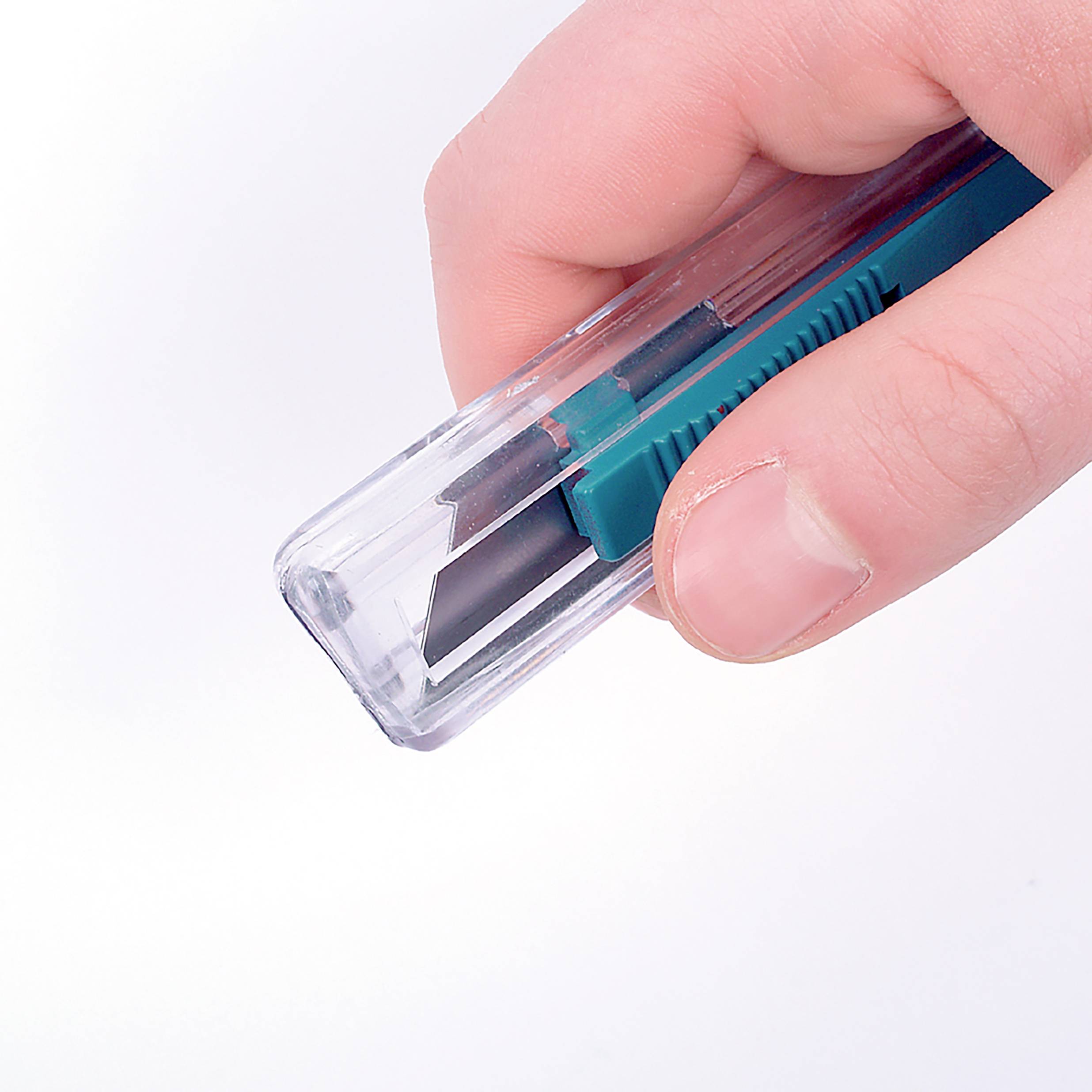 Eine Hand hält einen grünen Cutter mit ausgefahrener Klinge.