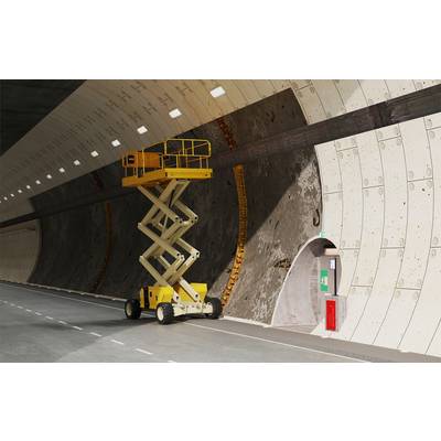 Gelber Scherenhubwagen in einem gekrümmten Tunnel neben einer Wand und einer Tür geparkt, vermutlich für Wartungsarbeiten.